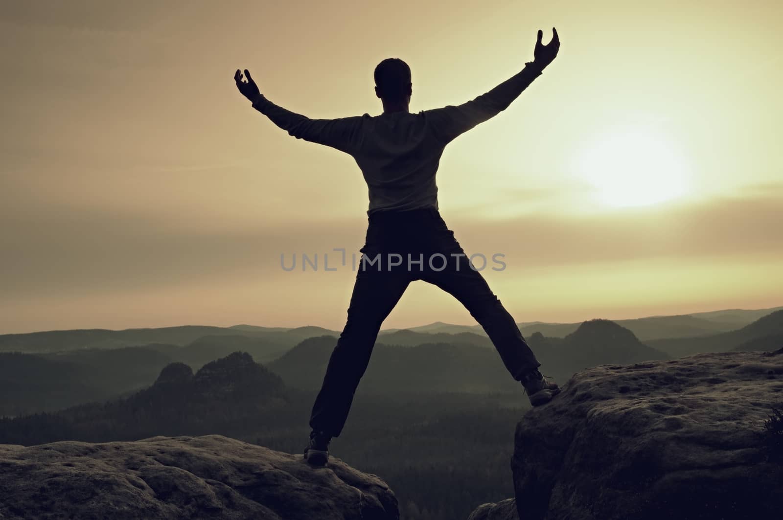 Sportsman in black with hands in pockets stand on the peak in rock empires park and watching over the mist by rdonar2