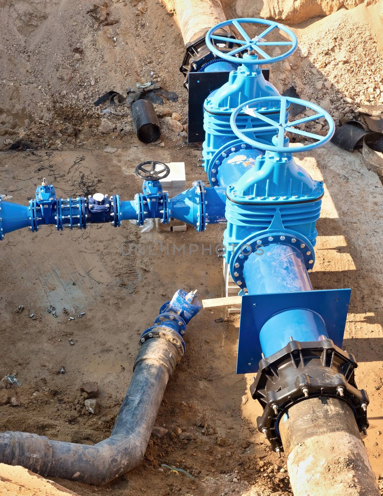 Oil, gas, water industry. Wellhead with valve armature underground. Dug deep trench utilities engineering urban systems.