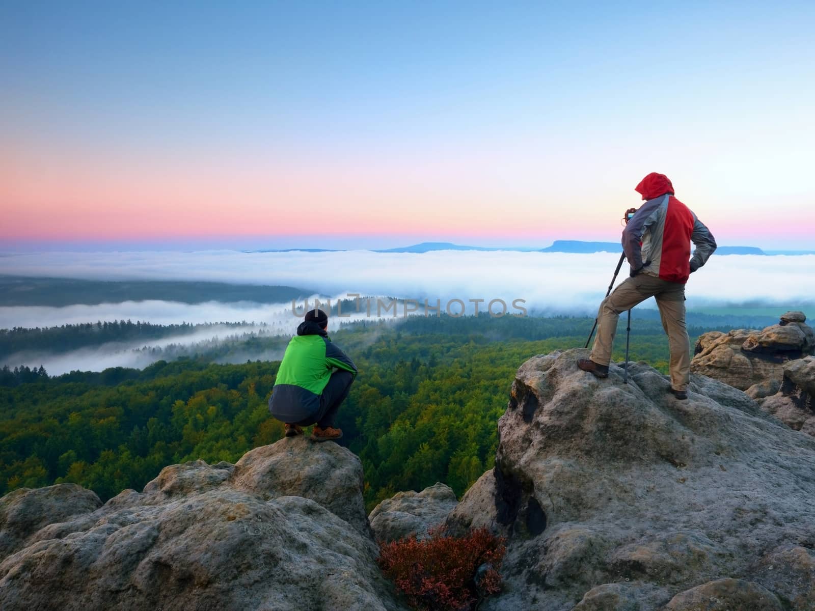 Hiker and photographer stay with tripod on cliff and takes photos. Autumn windy landscape, by rdonar2