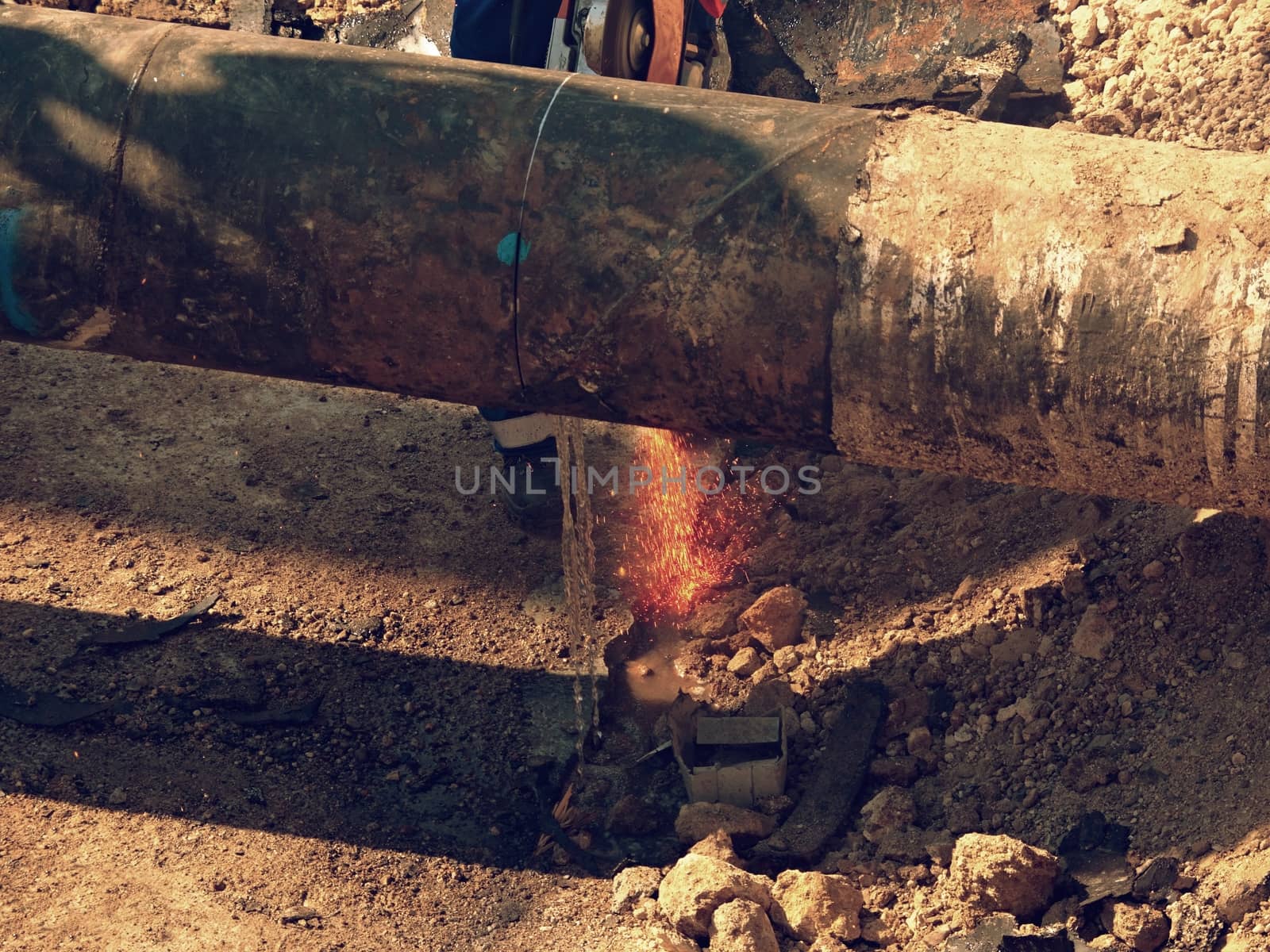 Man works, big pipe cutting with electric spiral machine. Hor sparks flying away from cut place.