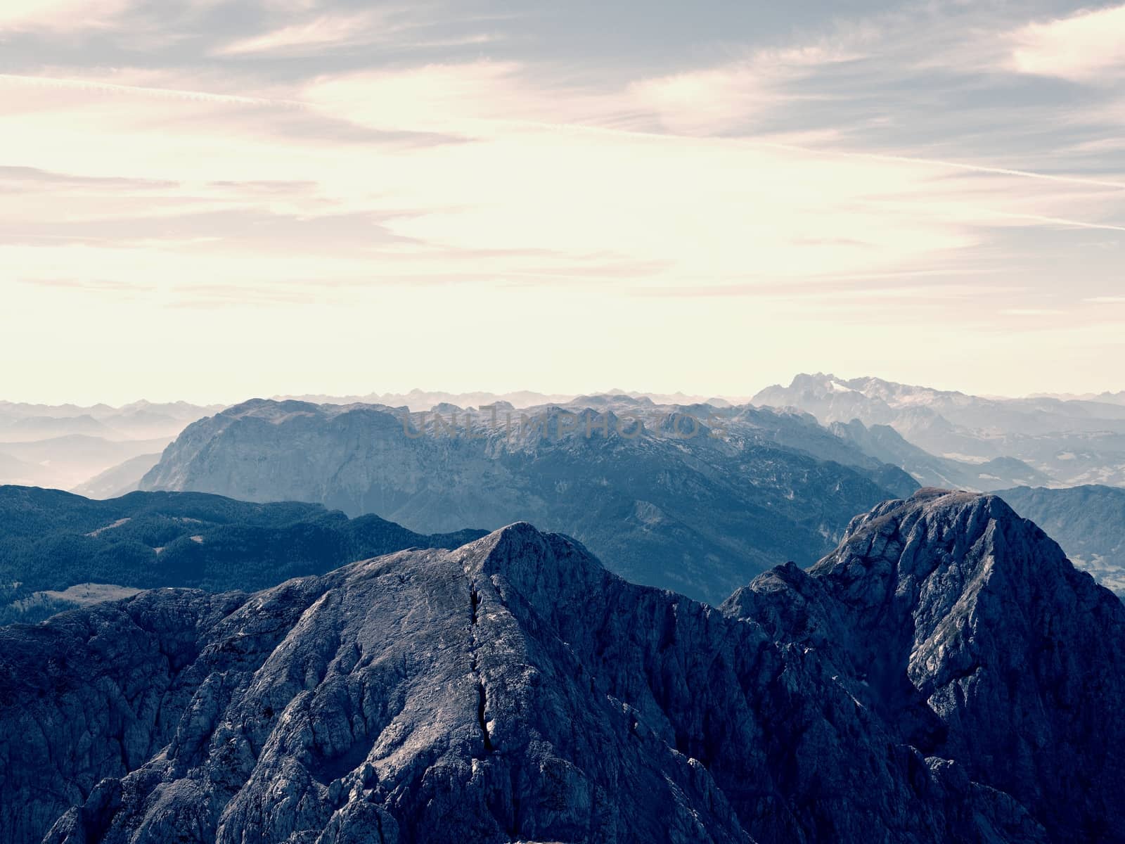 Spectacular aerial view of mountain silhouettes and misty valleys. Misty awaking of beautiful fairy valley. Peaks of rocks cut creamy foggy clouds.