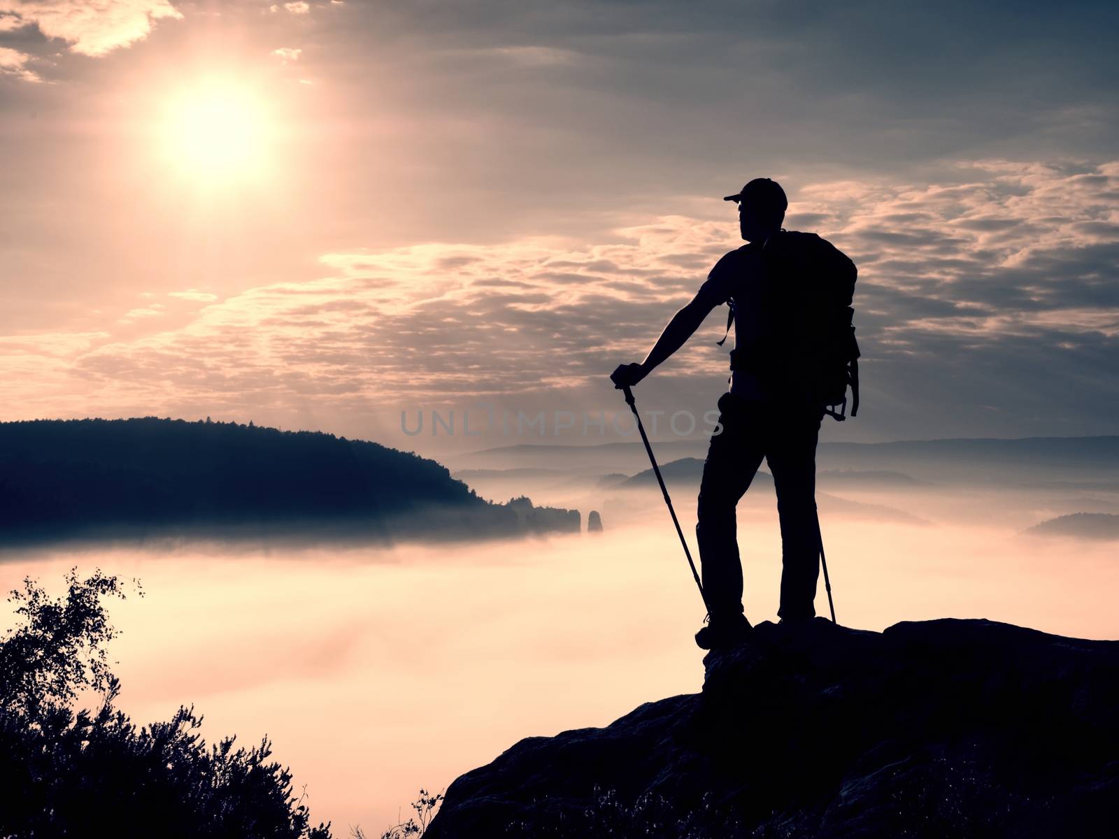 Tall tourist with poles in hand. View point above heavy misty valley.  by rdonar2