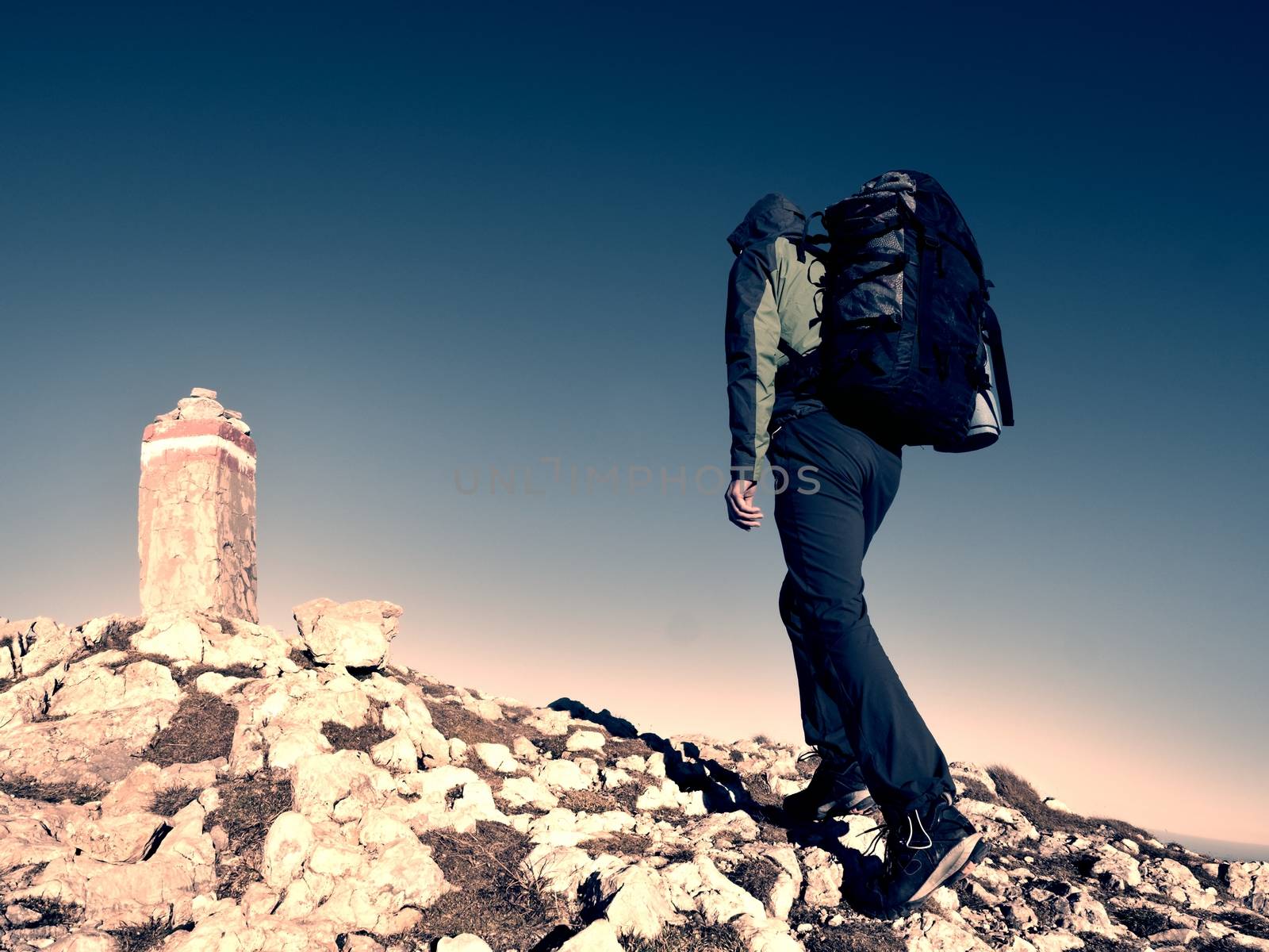 Hiker with backpack climbing on mountain peak. Summit stone in Alps by rdonar2