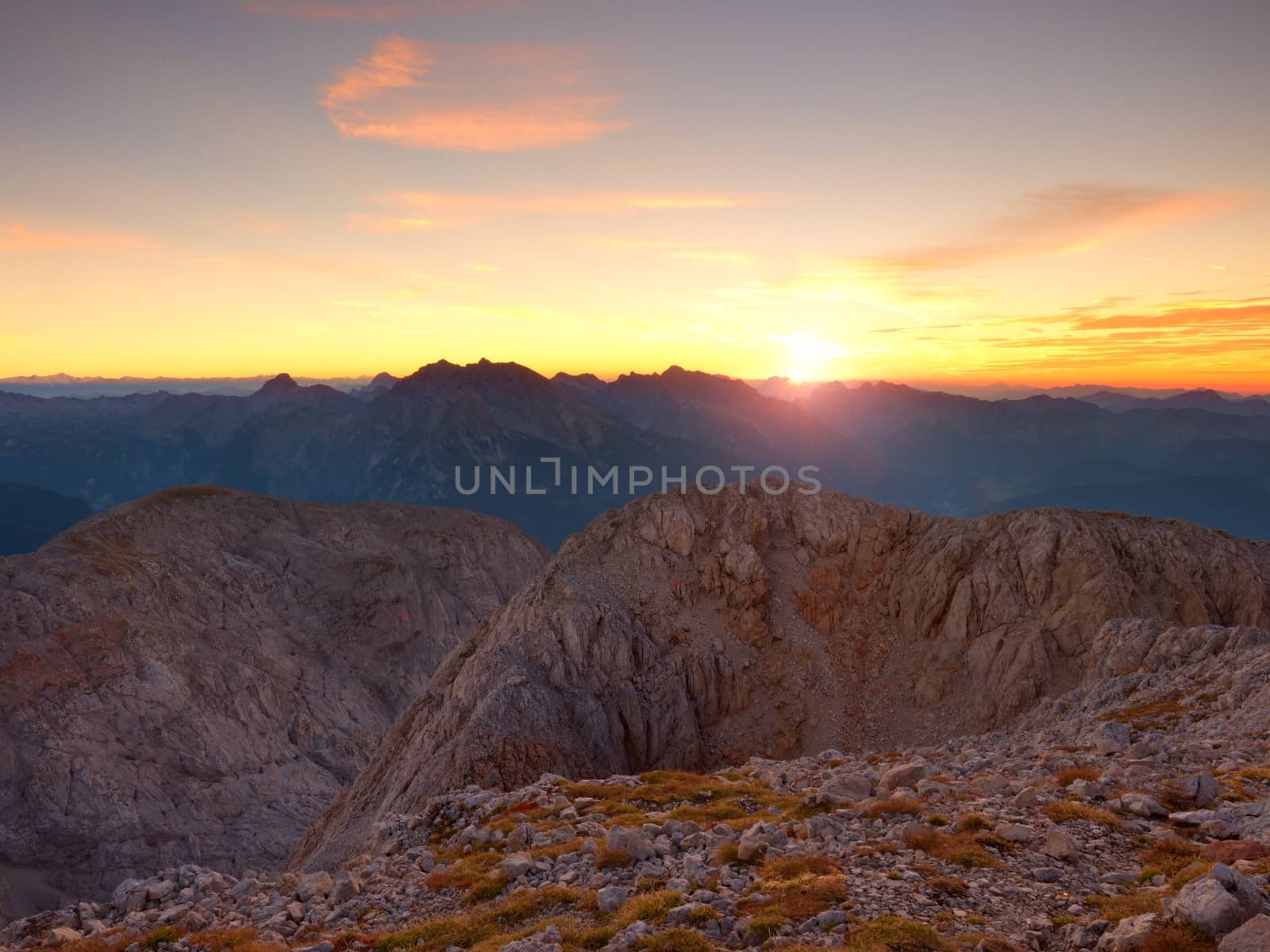 Morning view over Alpine  cliff and valley.Daybreak Sun at horizon. Mountains increased from foggy background