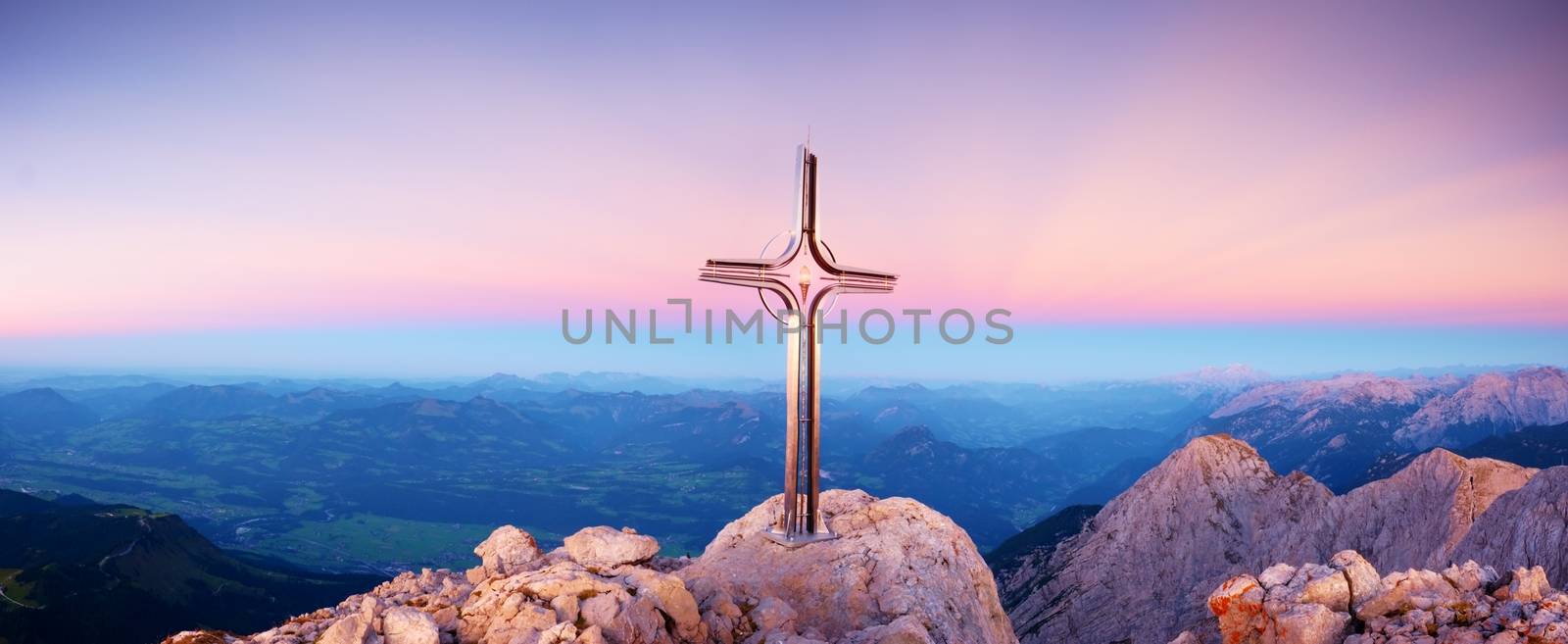 Hoher Goell autumn daybreak panorama. Iron cross at mountain top in Alp at Austria Germany border.  View to Tennen Range and Dachstein range, Berchtesgaden Alps.