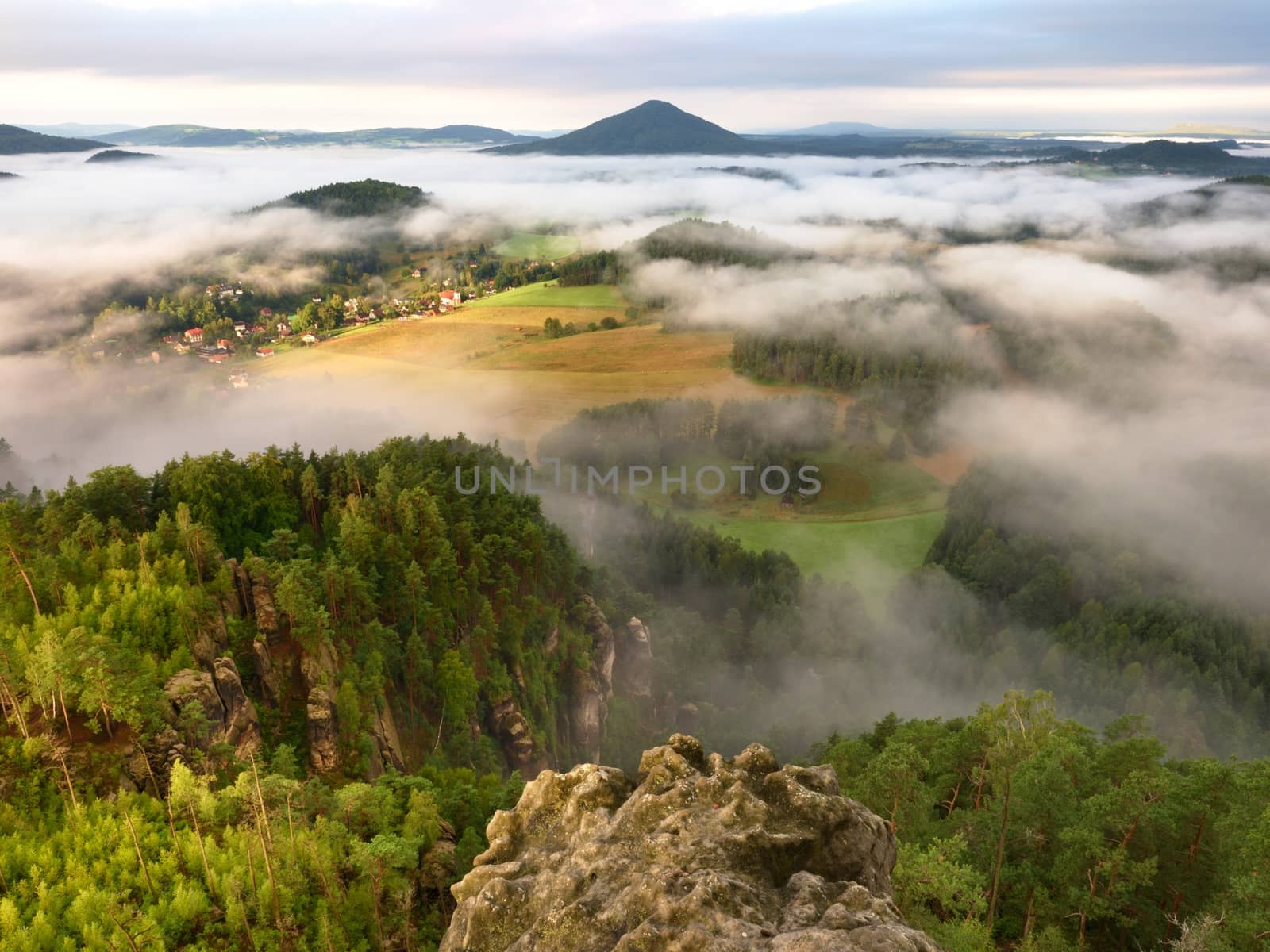Spring misty landscape. Morning in beautiful hills of natural park. Rocky peaks  increased from heavy creamy fog. 