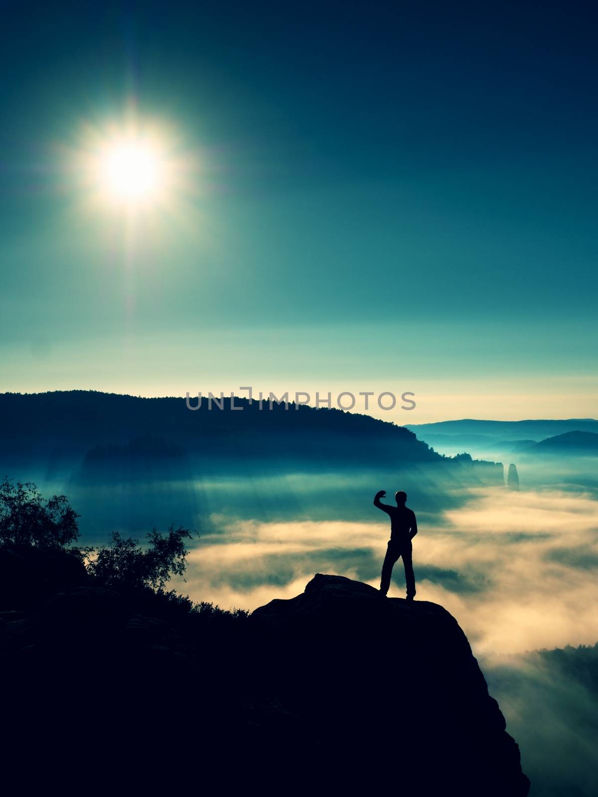 Man shadowing eyes. Alone tourist on cliff edge and watching into deep valley by rdonar2