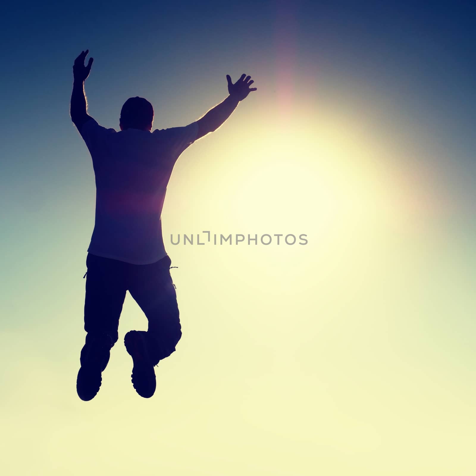 Crazy man is flying over Sun on blue sky background.  by rdonar2