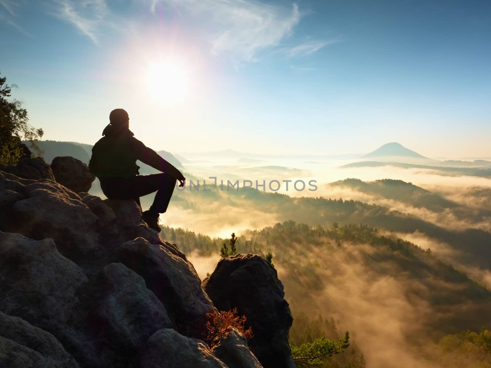 Hiker man take a rest on mountain peak. Man lay on summit, bellow autumn valley. by rdonar2
