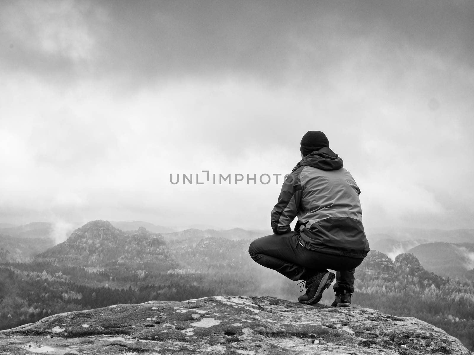 Hiker on rock end above valley. Man watch over misty and foggy valley  by rdonar2