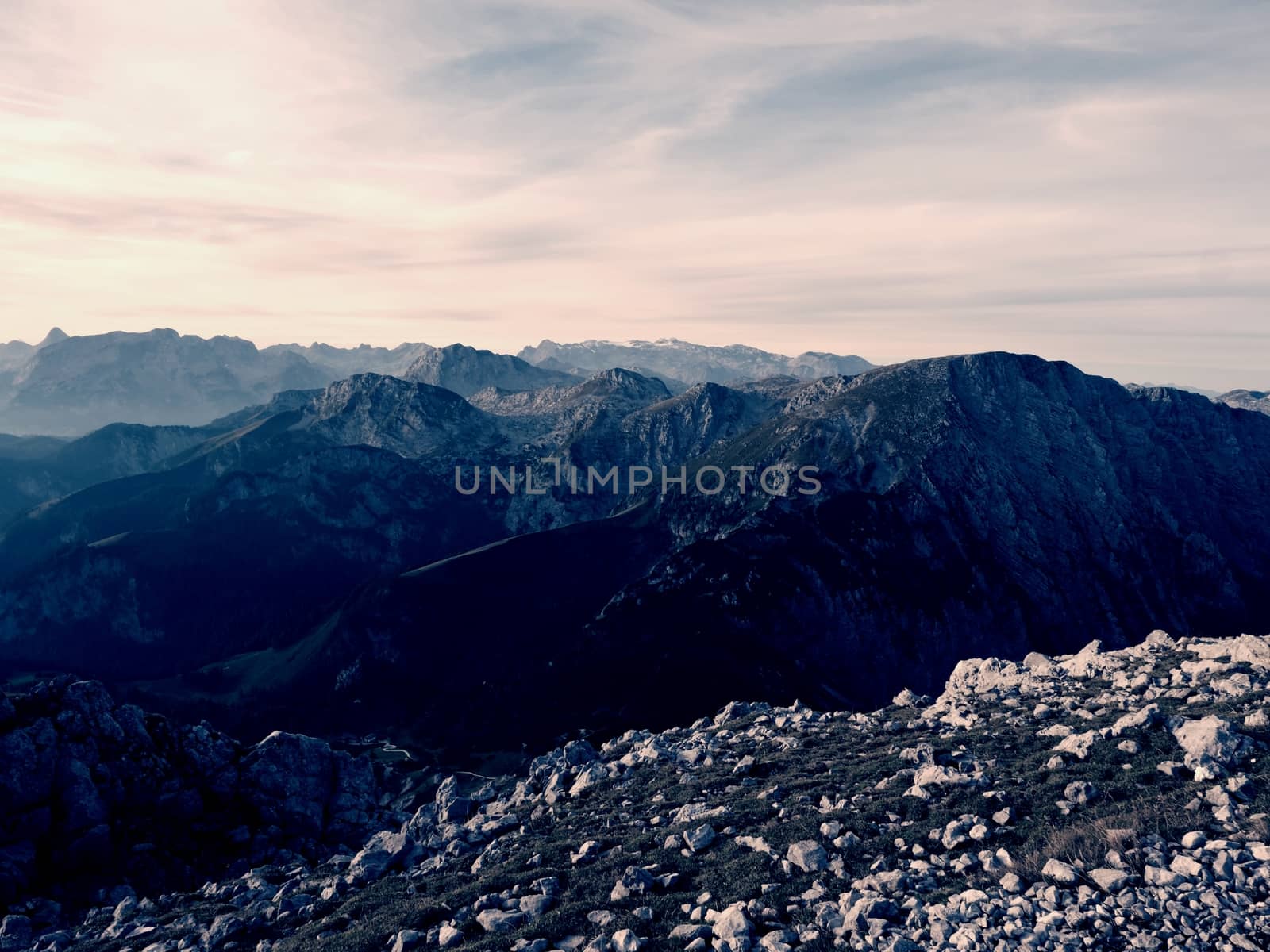Sharp Alps peaks, rocks without people. View over Alpine rocks above deep vallyes to far horizon. Sunny day with clear blue sky  
