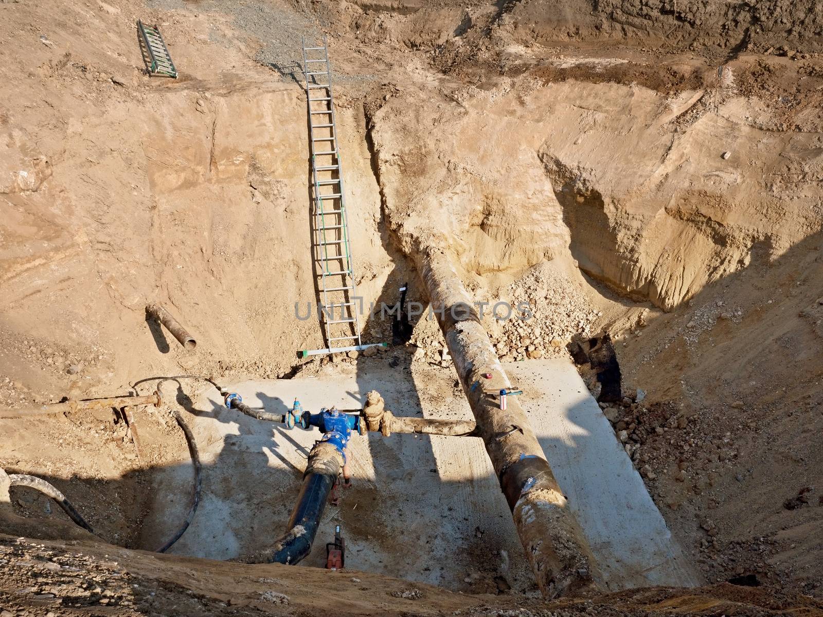 Excavation pit. Old 500mm drink water pipe with 150mm  cornering arm with gate valves, corroded  joining fittings.  Tubes before repair piping. Asphalt isolation. 