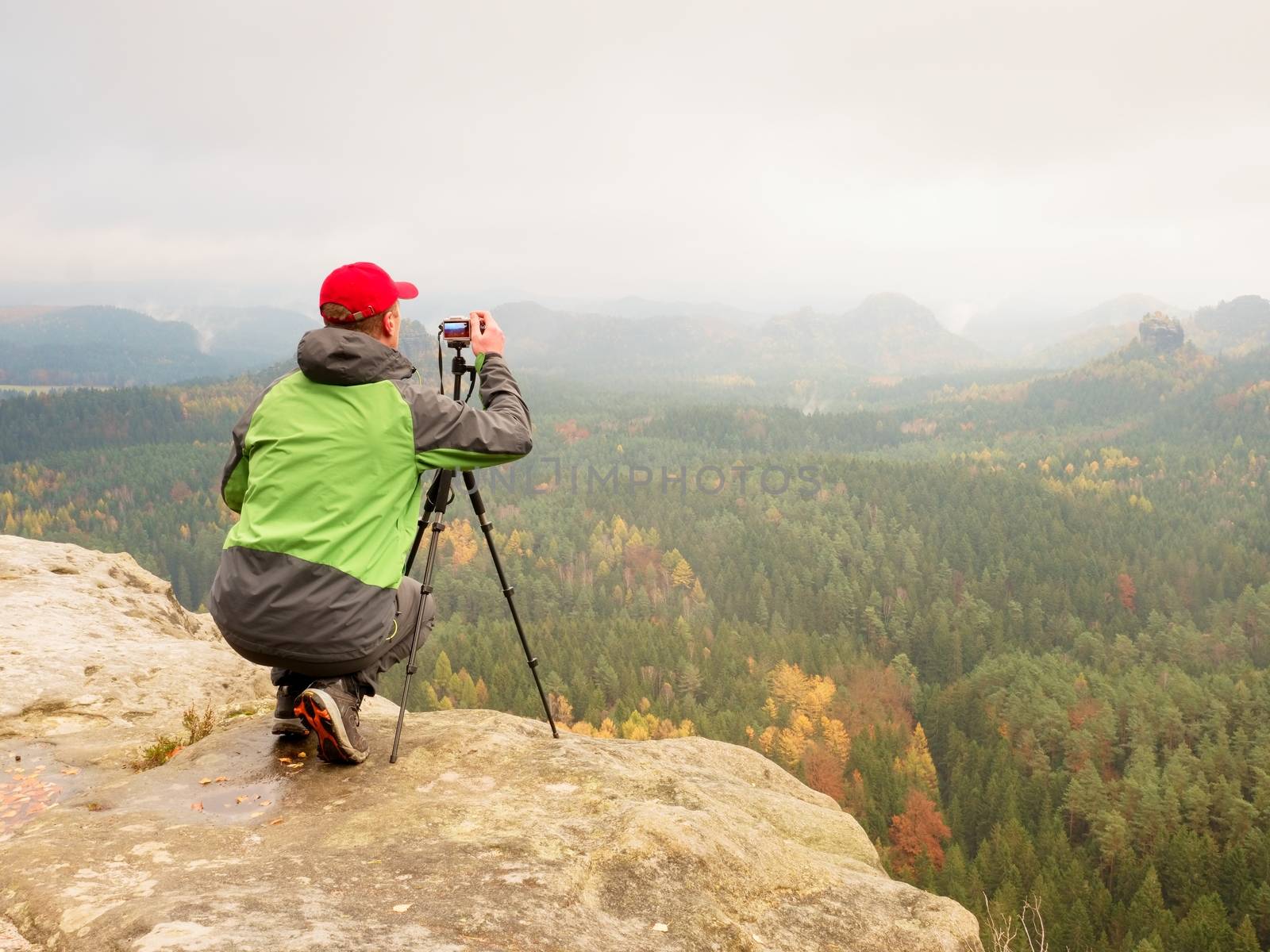 Nature photographer sit on rocky edge and takes photos  by rdonar2