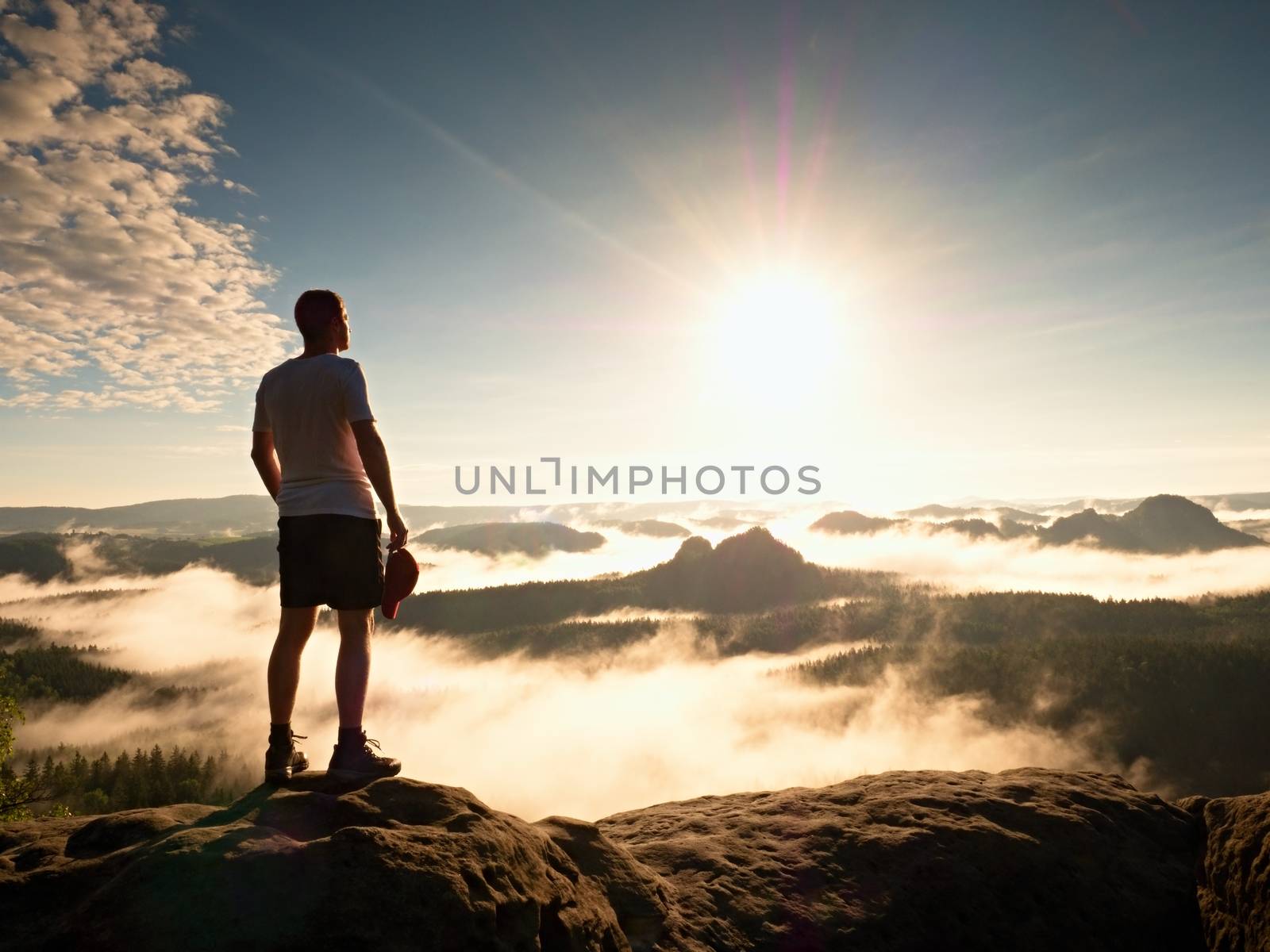 Tourist with red baseball cap sporty shorts stand on cliff edge by rdonar2