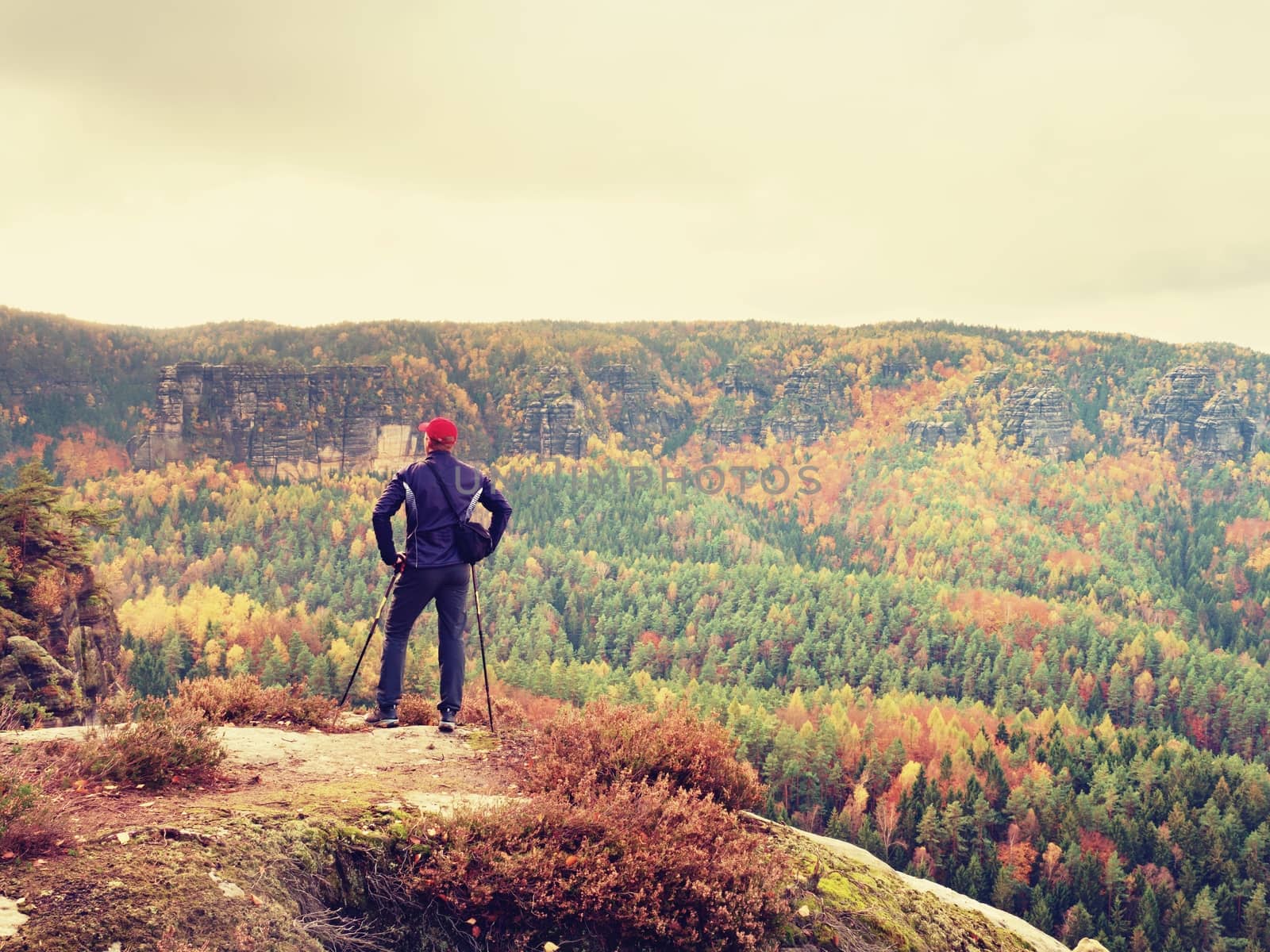 Hiker in sportswear stand on the peak of sandstone rock in rock empires park and watching over the autumnal colorful valley to Sun. Beautiful colors, the  miracle of nature 