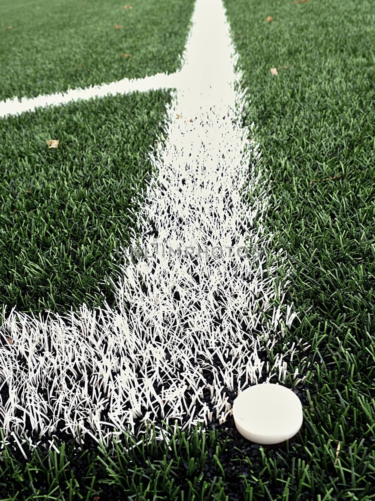 Football playground corner on heated artificial green turf ground with painted white line marks. Milled black rubber in basic of ground.