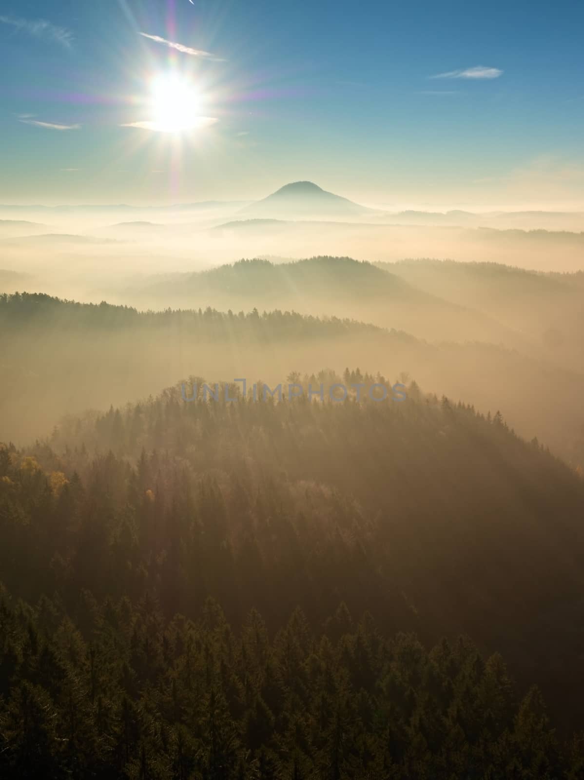 Fall daybreak. Misty awakening in a beautiful hills. Peaks of hills are sticking out from foggy landscape 