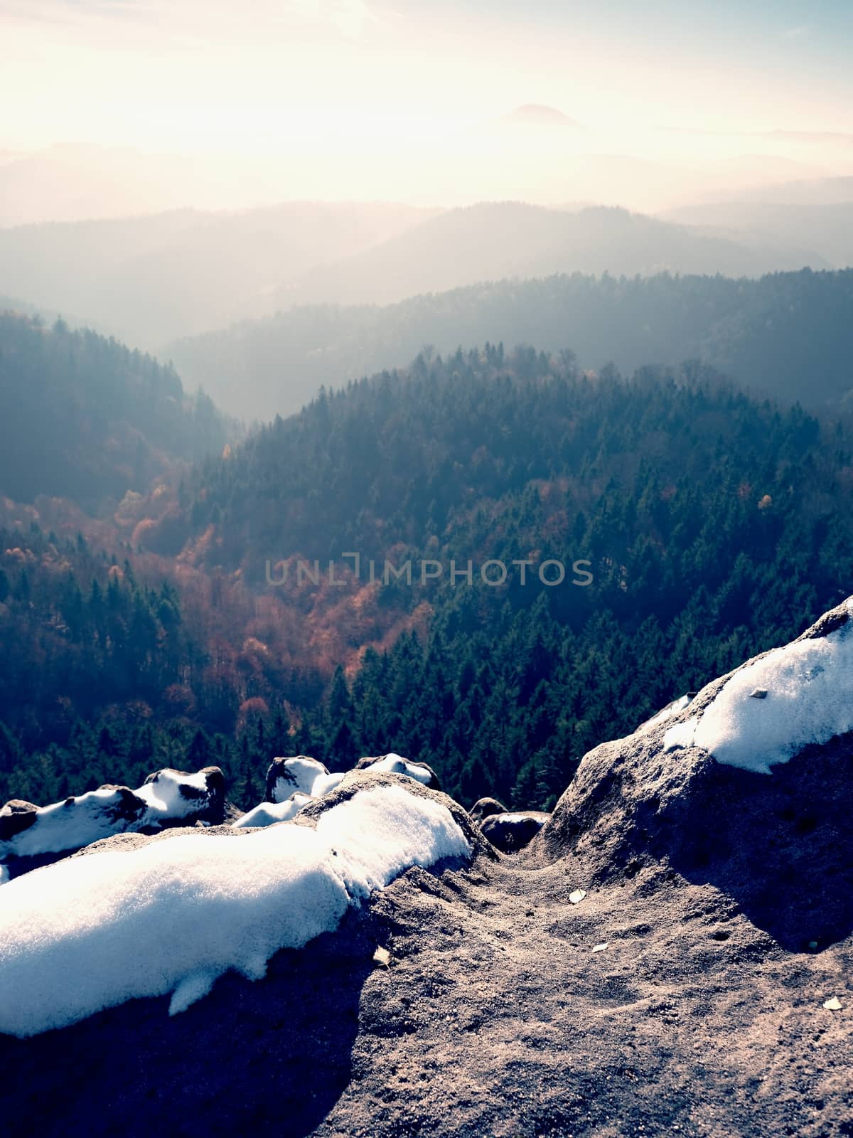 Rocky peak above inverse mist. Winter cold weather in mountains, colorful fog. Misty valley in winter mountains. Peaks of  mountains above creamy mist. 