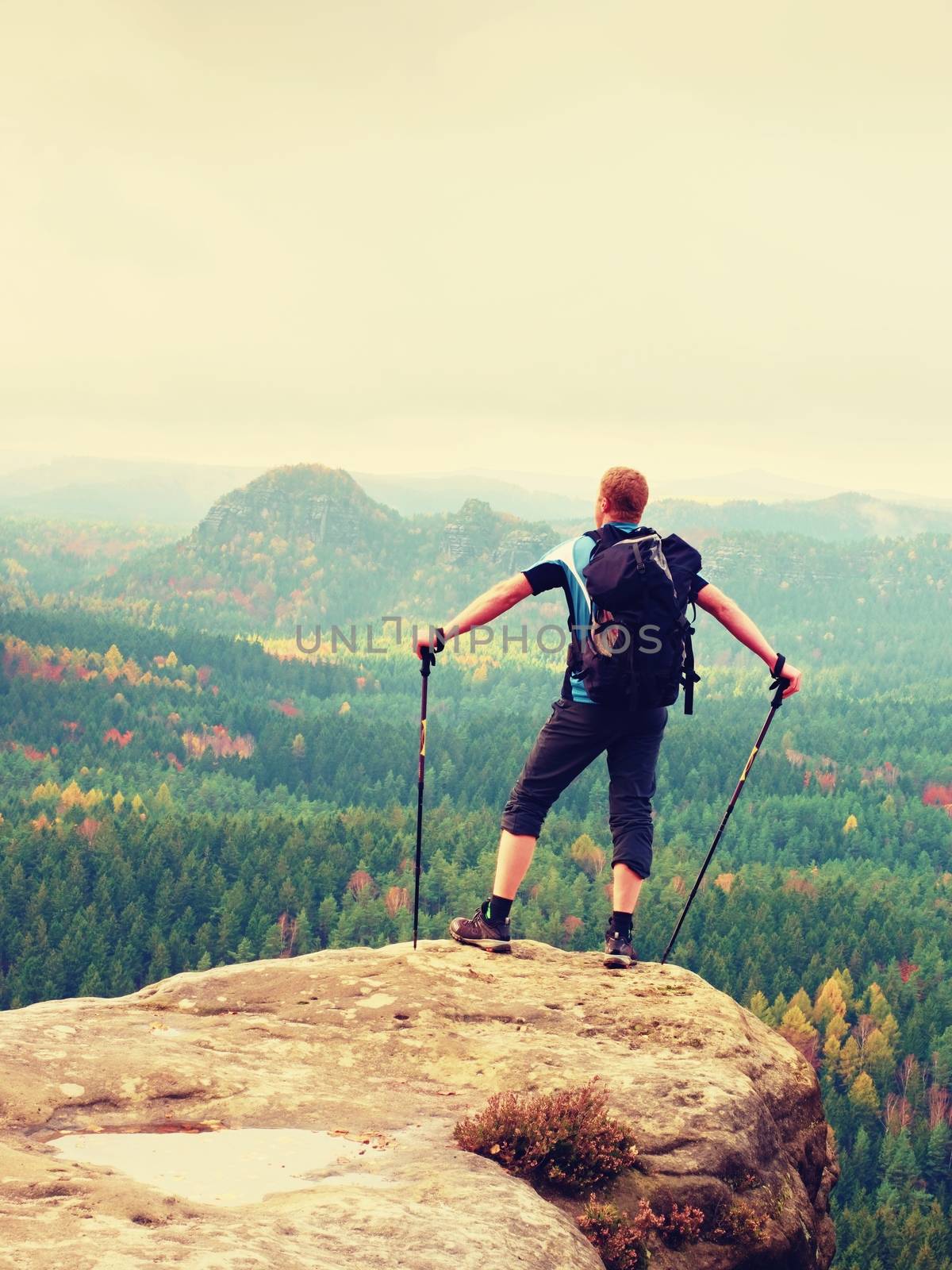 Tourist with big backpack stand on rocky view point and watching to colorful autumnal country by rdonar2