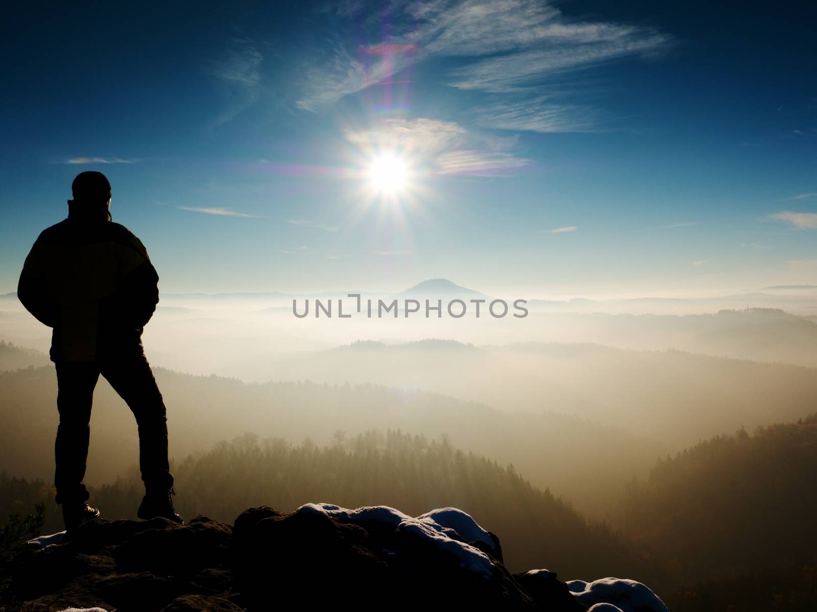 Man silhouette stay on sharp rock peak. Satisfy hiker enjoy view. Tall man on rocky cliff watching down to landscape. Vivid and strong vignetting effect.
