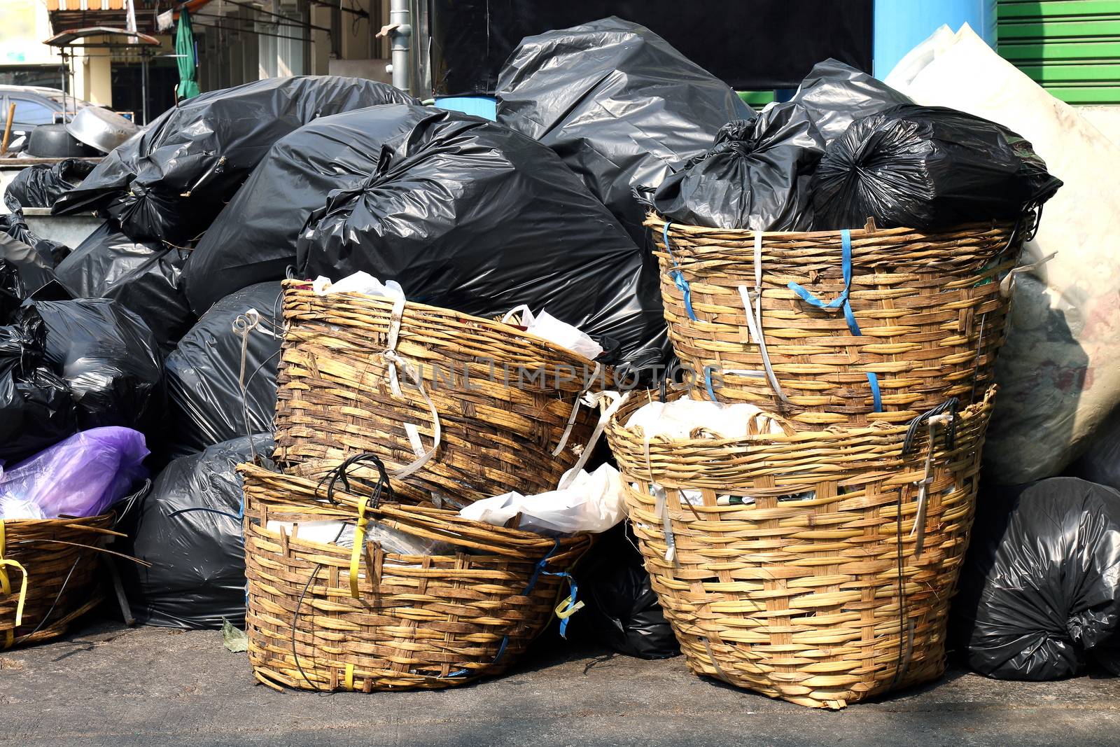 waste plastic junk in basket, pile garbage bamboo rattan baskets bags on the floor and many dump black plastic garbage bags