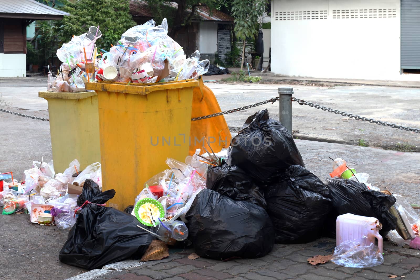 Pile of Garbage plastic black and trash bag waste many on the footpath, pollution trash, Plastic Waste and bag foam tray garbage many on floor, Waste plastic are background people walking at the road