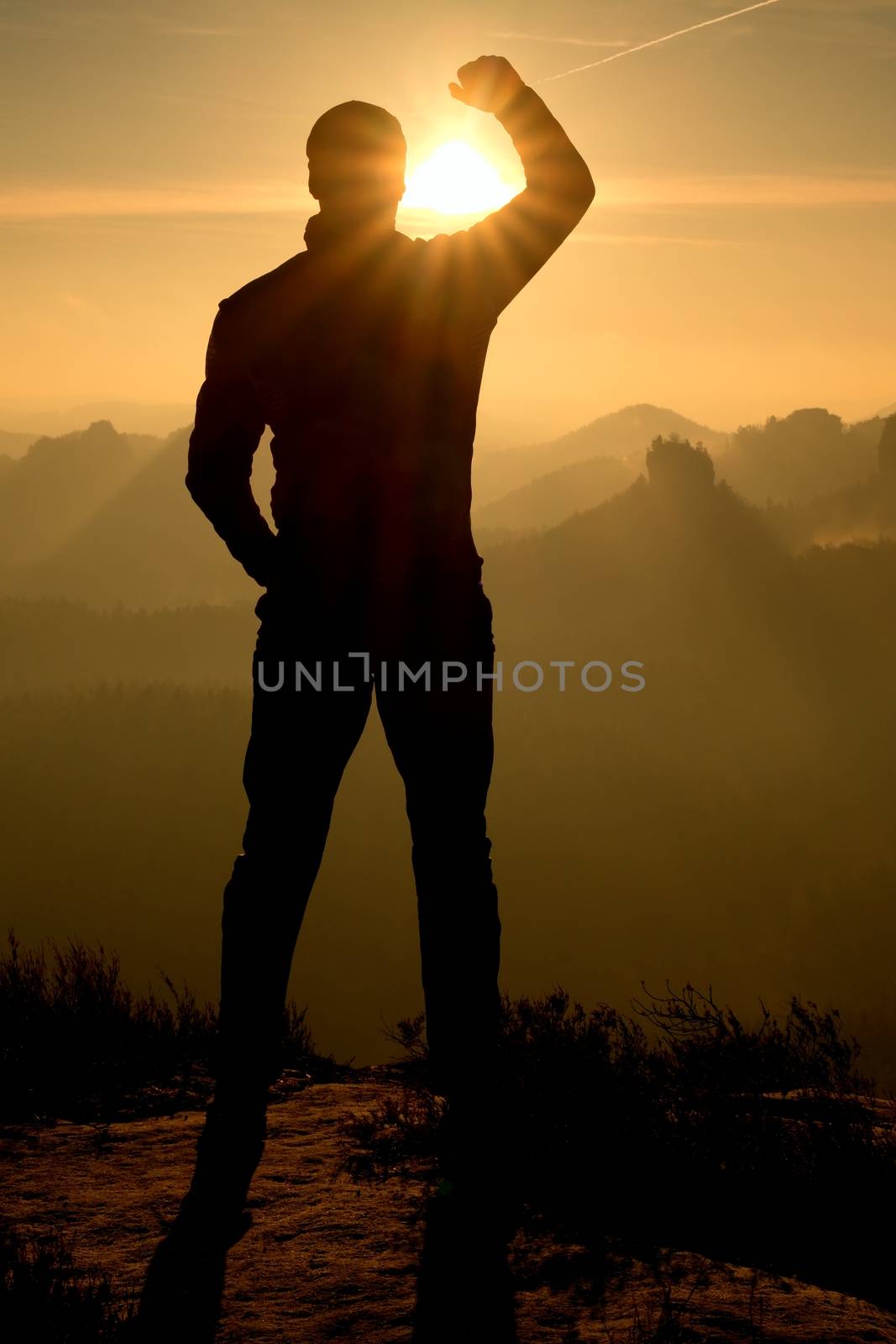 Self confident hiker on the peak of sandstone rock in rock empires park and watching over the misty and foggy morning