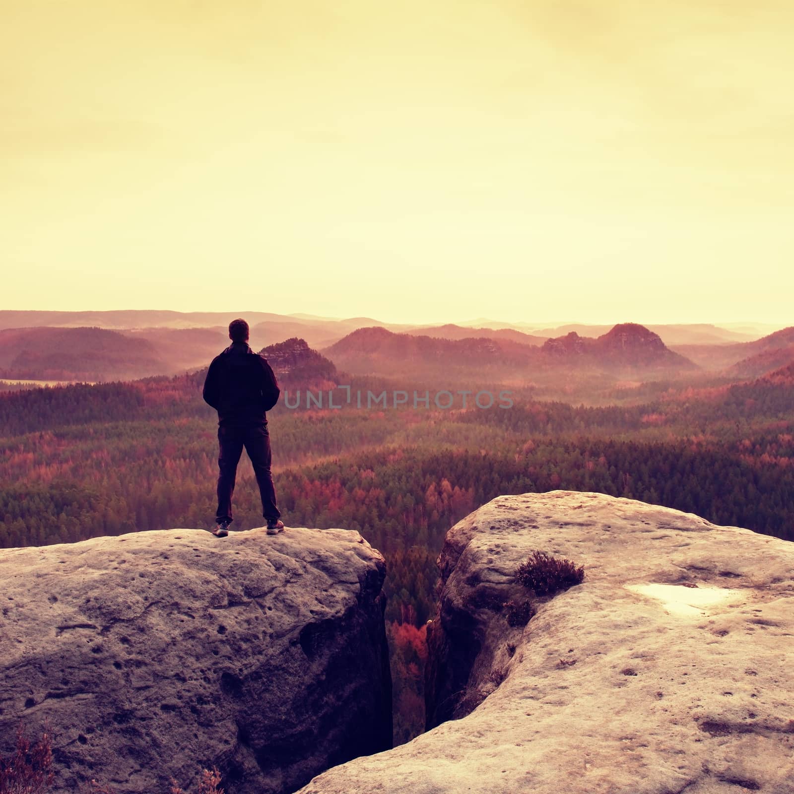 Silhouette of man on sharp cliff in  mountains within spring daybreak. Conceptual scene.