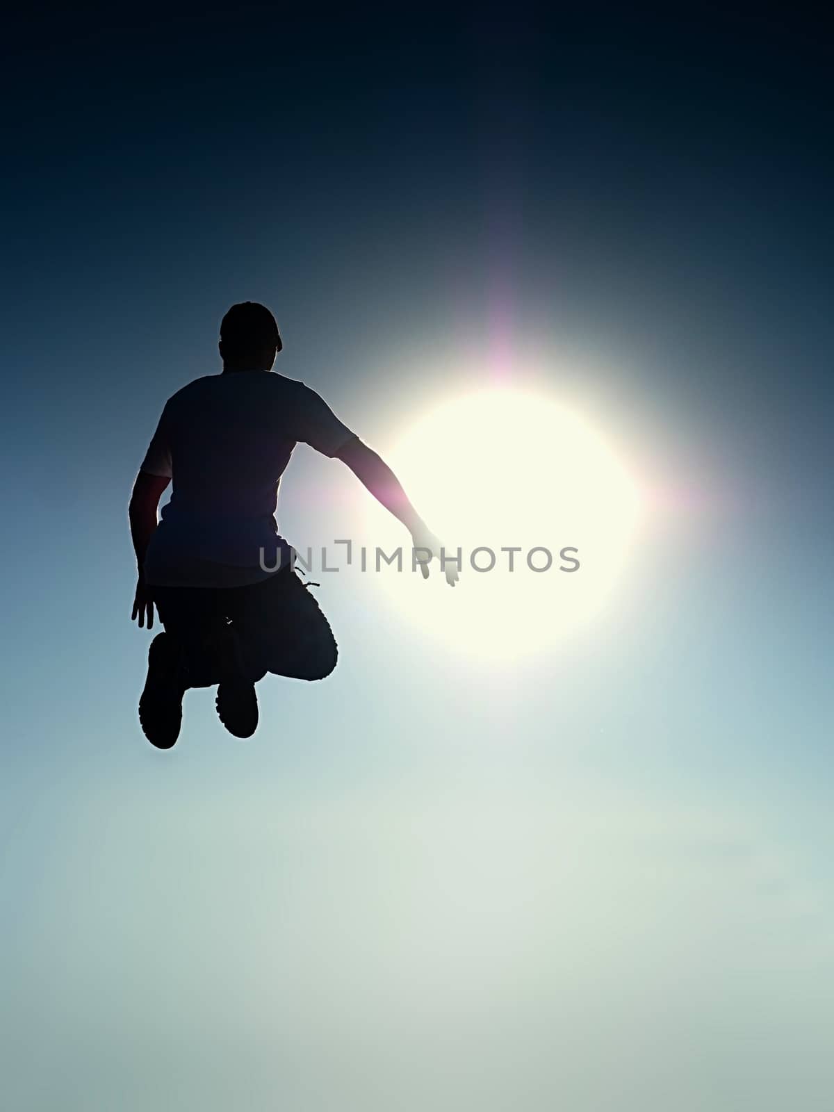 Flying man. Young man falling down over Sun in colorful sky. Silhouette of poise man and beautiful sunset sky. Element of design. Vintage effect.