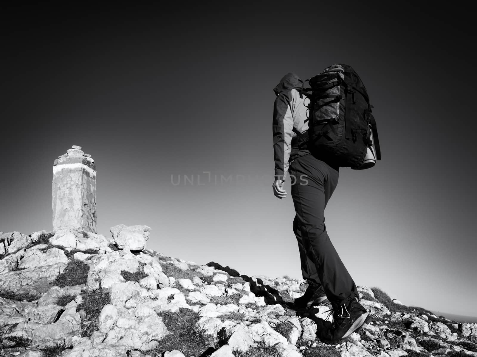 Adult tourist with backpack walk on mountain peak. Last step to summit stone on mountain top. Tourist walk with  heavy backpack  