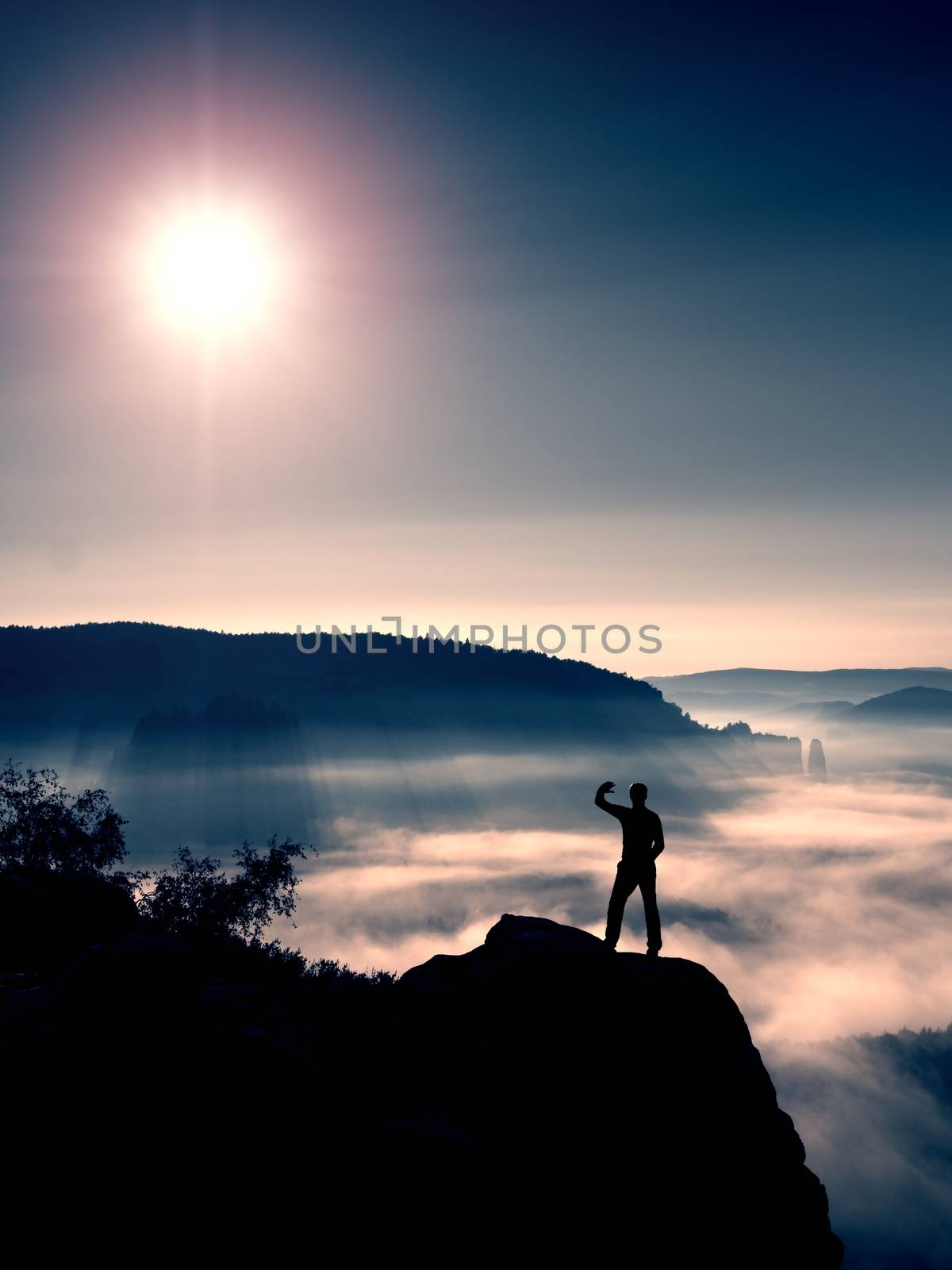 Man shadowing eyes. Alone tourist on cliff edge and watching into deep valley by rdonar2