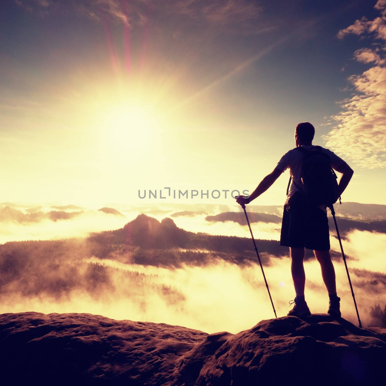 Man tourist sit on exposed rock. View point with sharp rock above misty valley by rdonar2