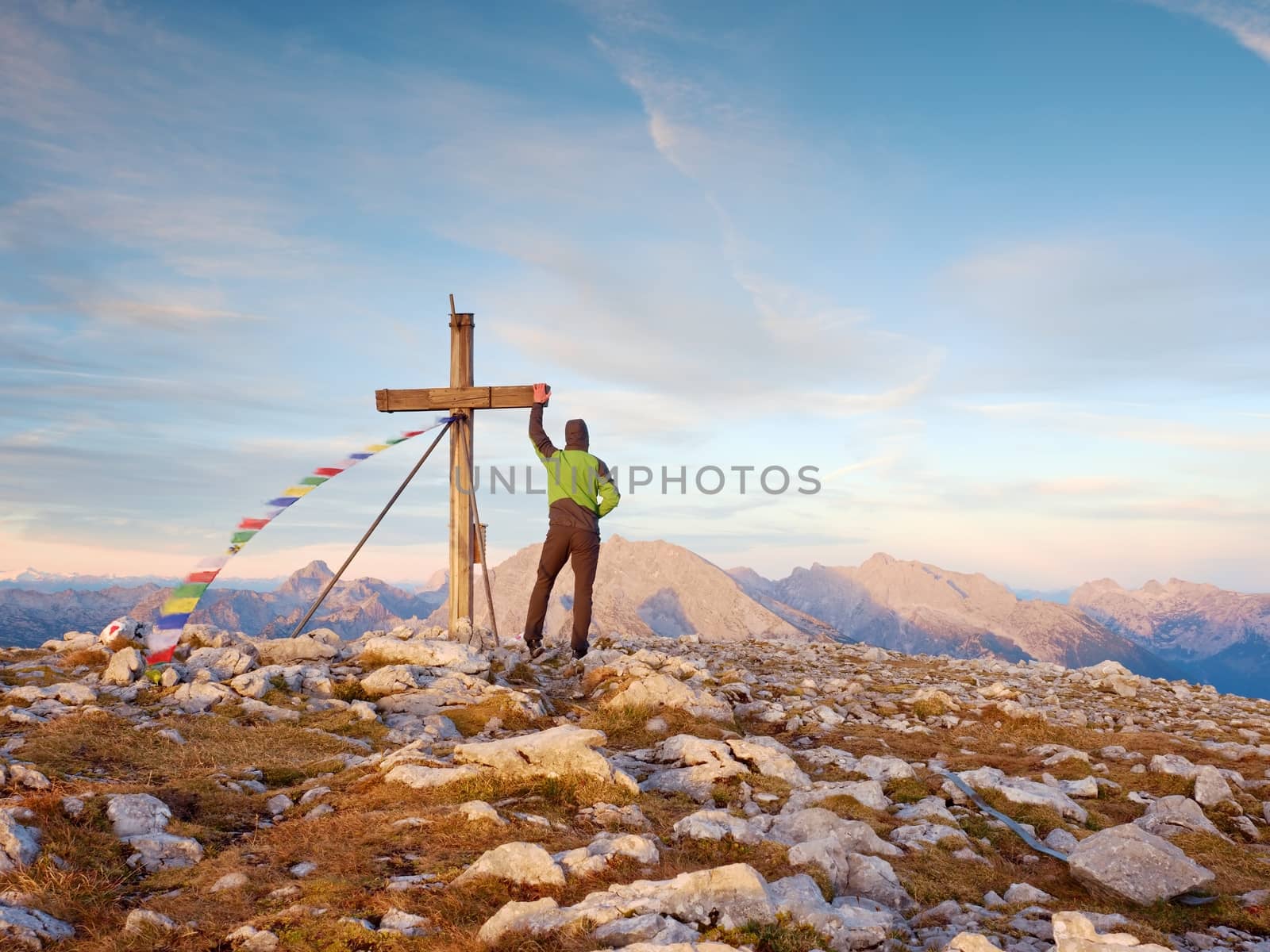 Tourist stand on rocky view point and watching into misty Alpine valley. Wooden cross at a mountain peak. Cross on top of a mountain peak as typical in the Alps. 