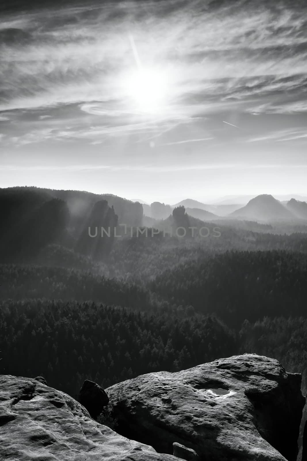 Misty daybreak in beautiful hilly landscape. Peaks of hills are sticking out from foggy valley. Black and white photo.