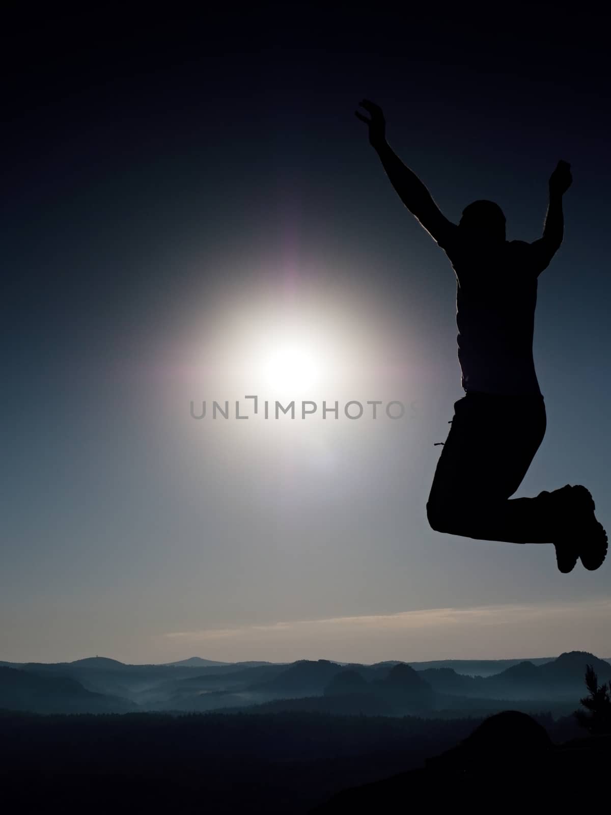 Jumping man. Young crazy man is jumping on colorful sky background.Silhouette of jumping man and beautiful sunset sky. Element of design. Vintage effect.