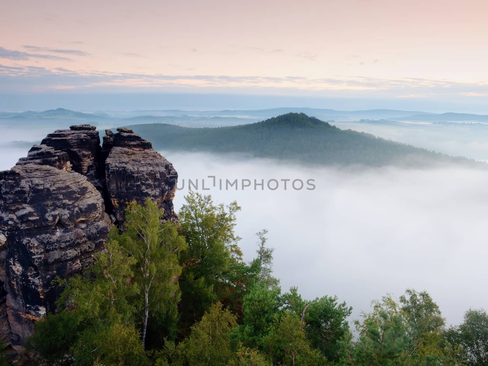 Sharp sandstone cliffs above deep misty valley. Popular climbers resort. Rocks sticking up from fogy lanscape to sky