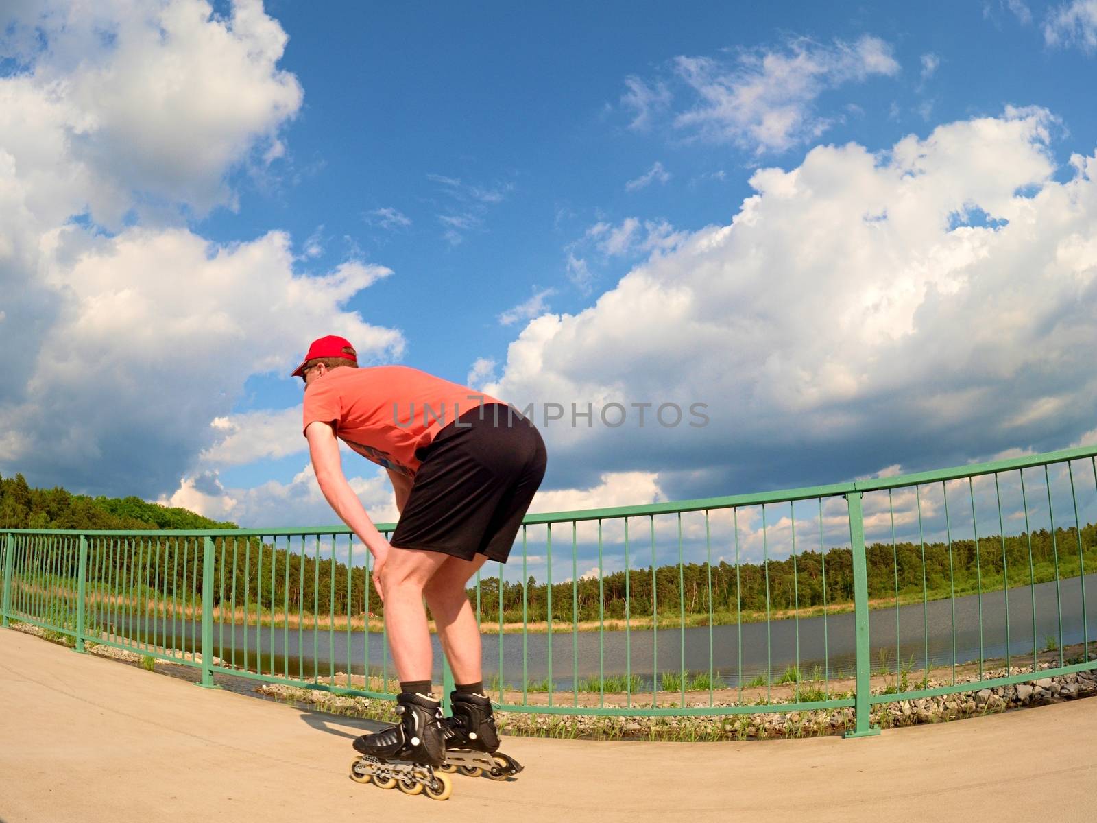 Rear view to inline skater in red t-shirt and black pants skating on the bridge . Outdoor inline skating  by rdonar2
