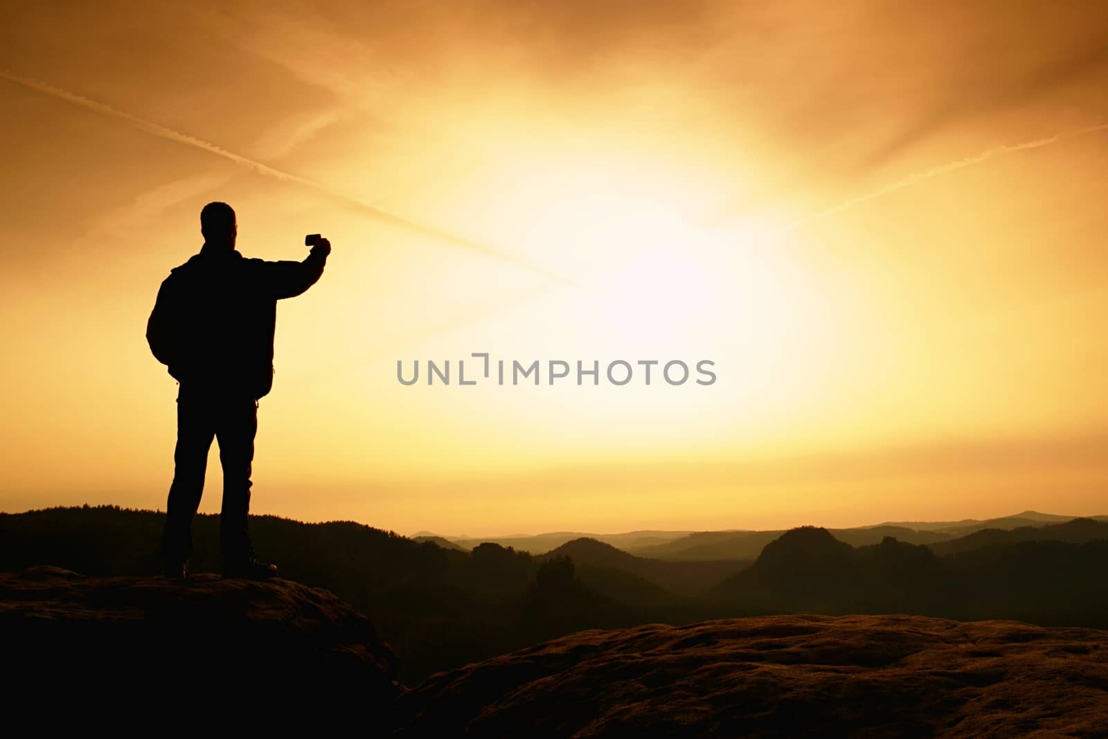 Tourist hold in hand shinning phone and phototograph spring hilly landscape. Misty natuure. Phone photography on the peak of mountain at sunrise.