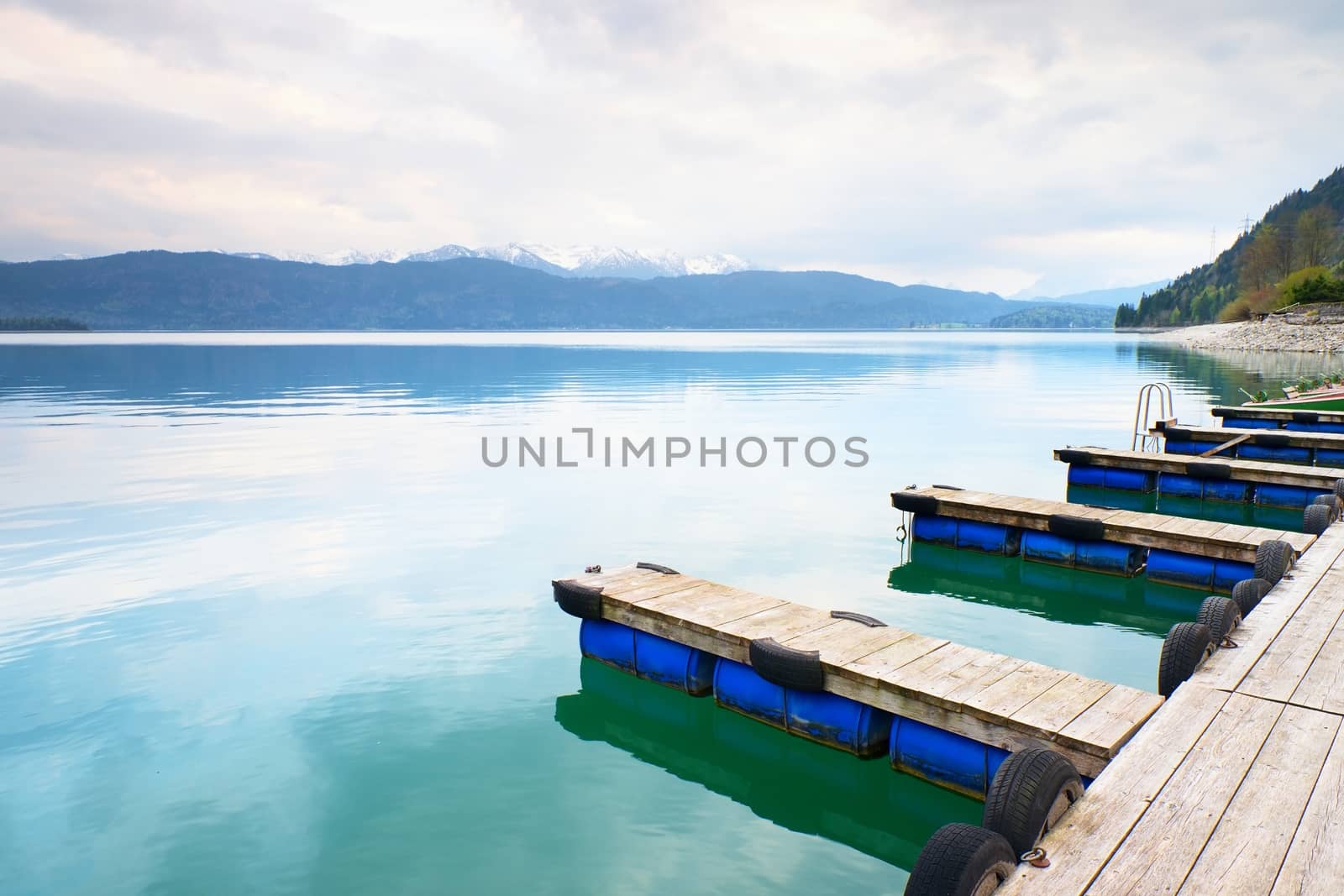 Blue Alps lake with Rental rowing boats in marina. Wharf for trip ships.