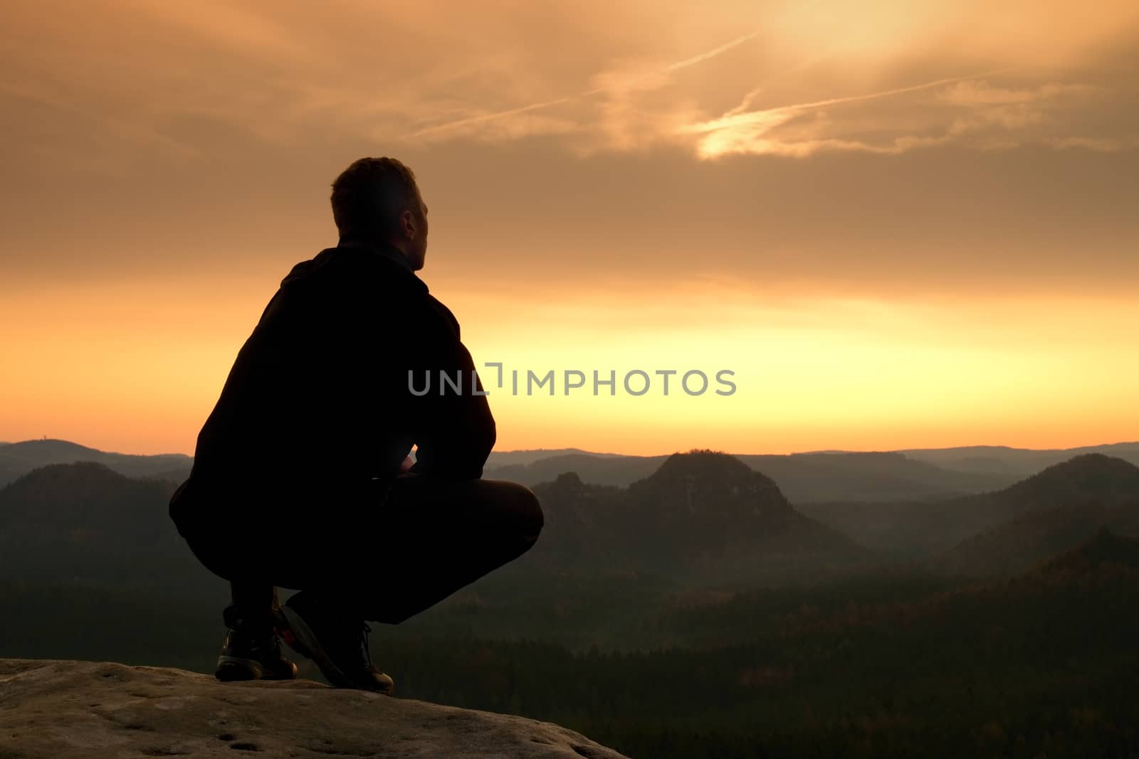 Short hair hiker in shirt sit on rock, enjoy foggy scenery by rdonar2