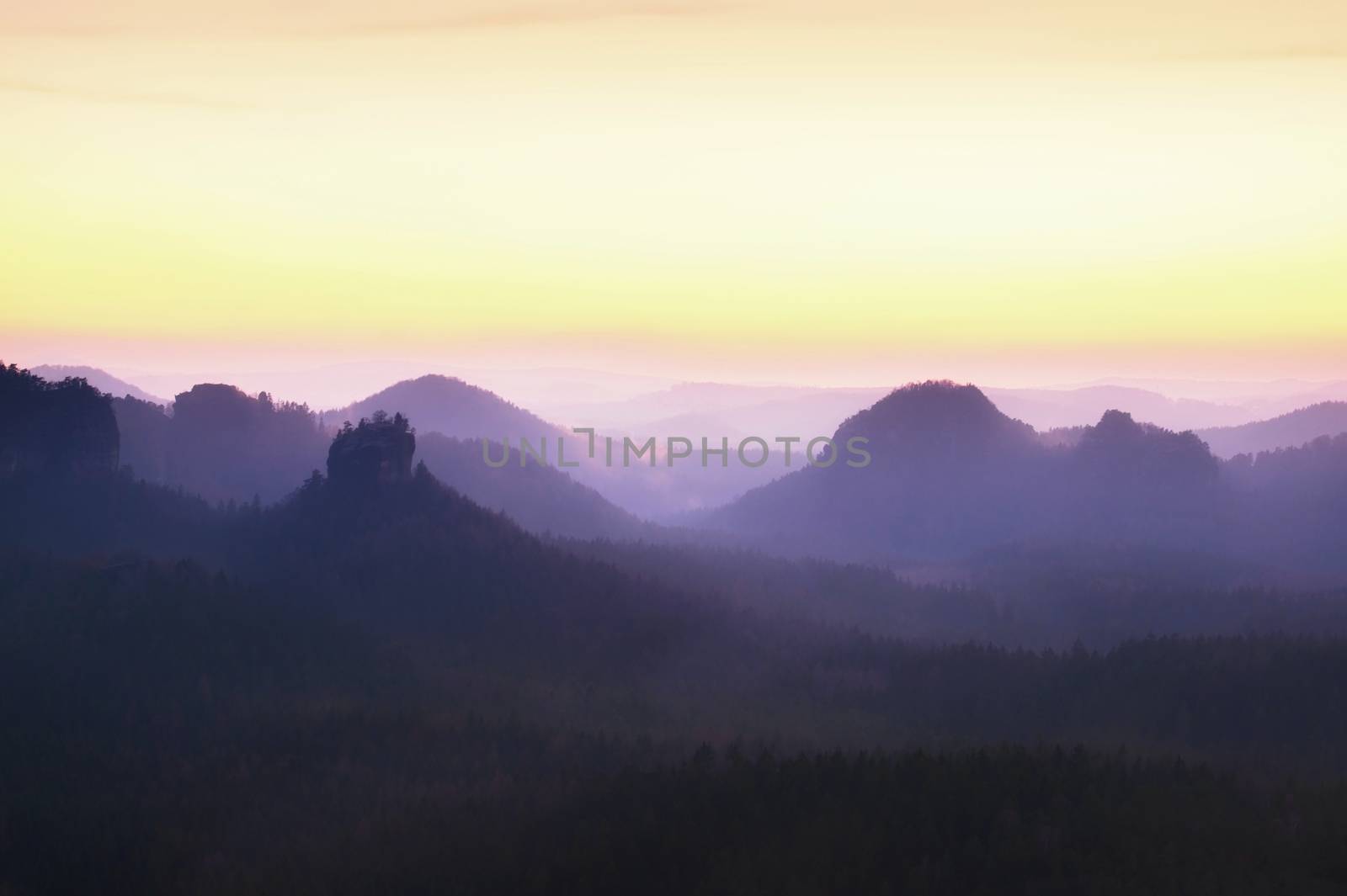 Tourist resort. Fantastic dreamy sunrise on the top of the rocky mountain with the view into misty valley. Vivid dreamy effect.