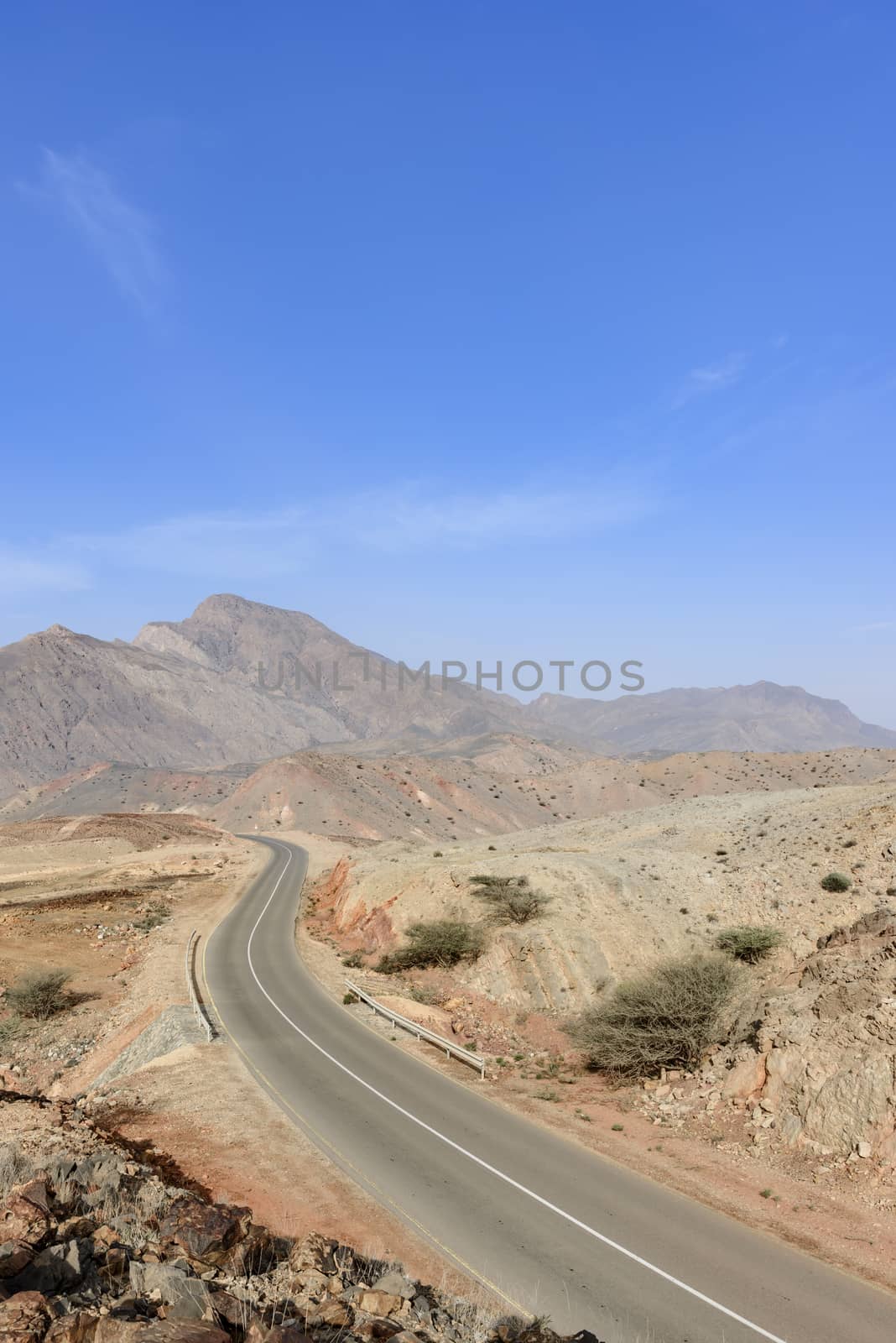 A road going thru the deserted mountains of the Sultanate of Oman