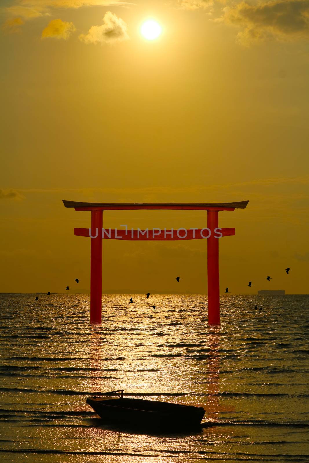 reflection torii sunset orange cloud on the sky and silhouette birds flying on the sea vertical view