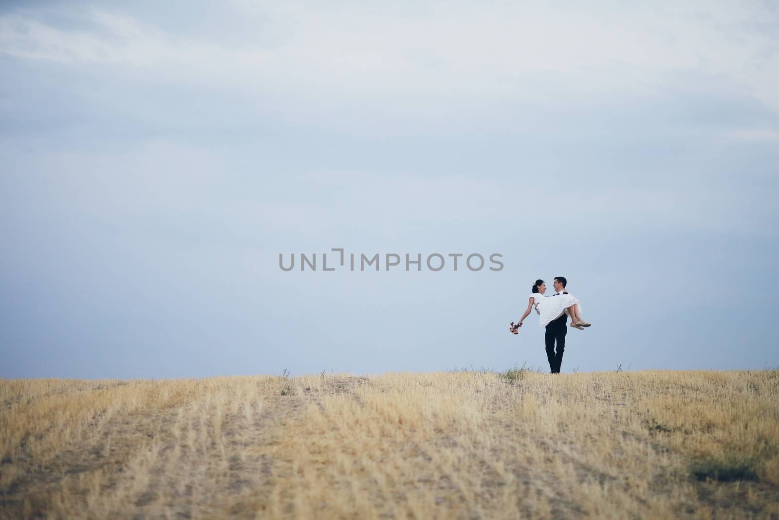 The bride and groom hold hands, hug each other and walk in the park. wedding by selinsmo