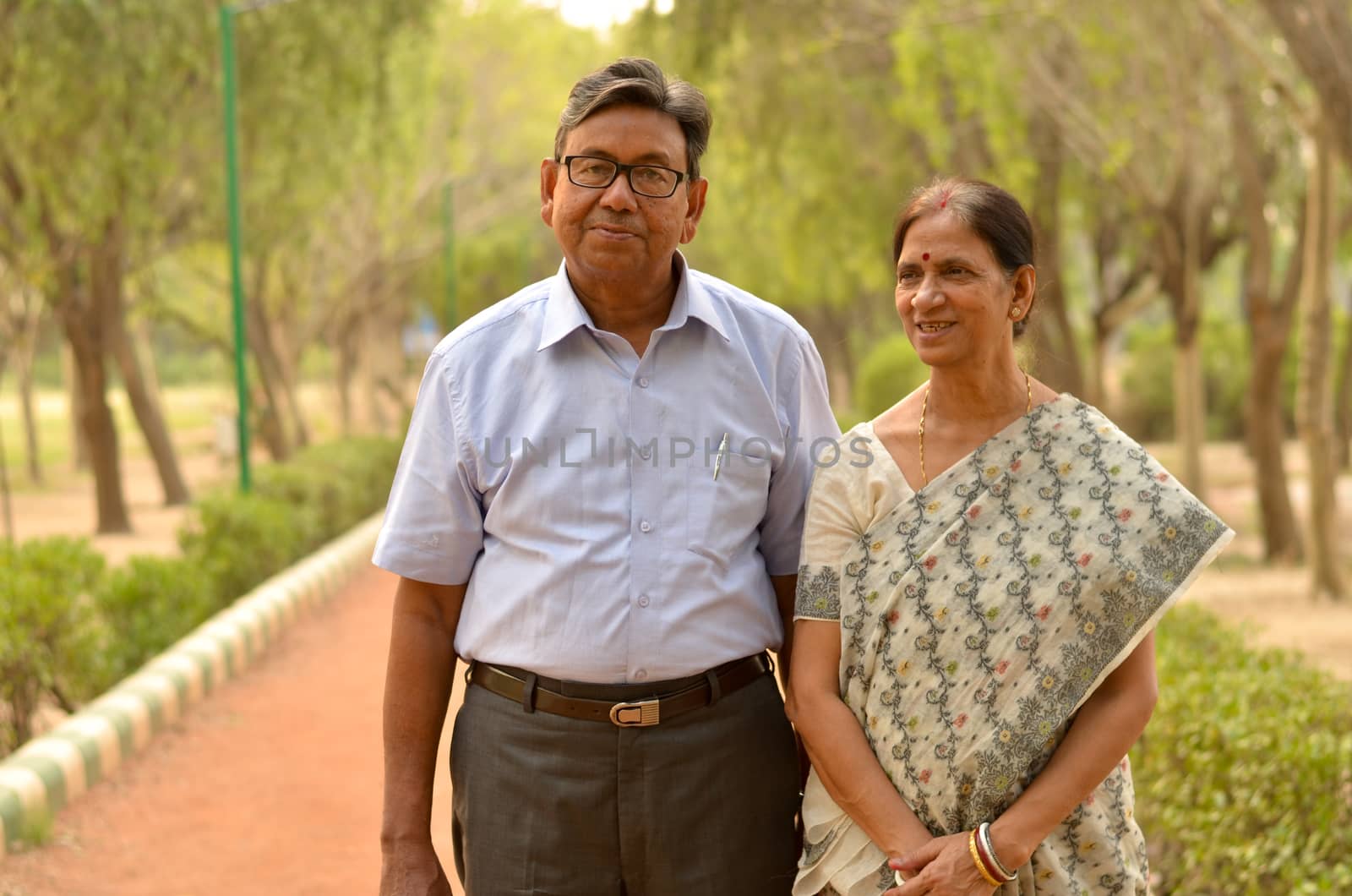 Happy looking retired senior Indian man and woman couple smiling and posing in a park outdoor setting in New Delhi, India. Concept love