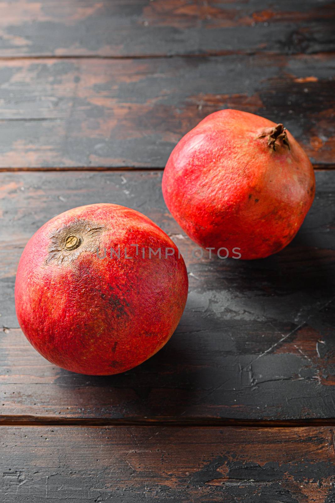 Ripe pomegranates over dark old wooden table, side view close up. by Ilianesolenyi