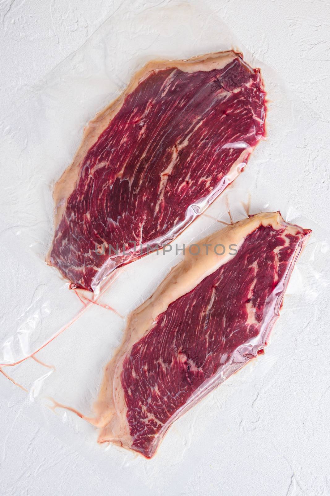 Raw picanha steak vacuum packed organic beef meat on white concrete textured background, top view. by Ilianesolenyi