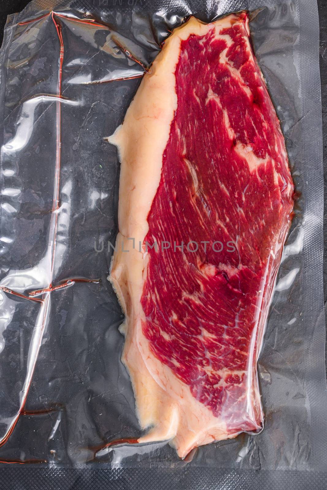 Picanha beef steak for sous vide cooking on black stone background, top view. by Ilianesolenyi