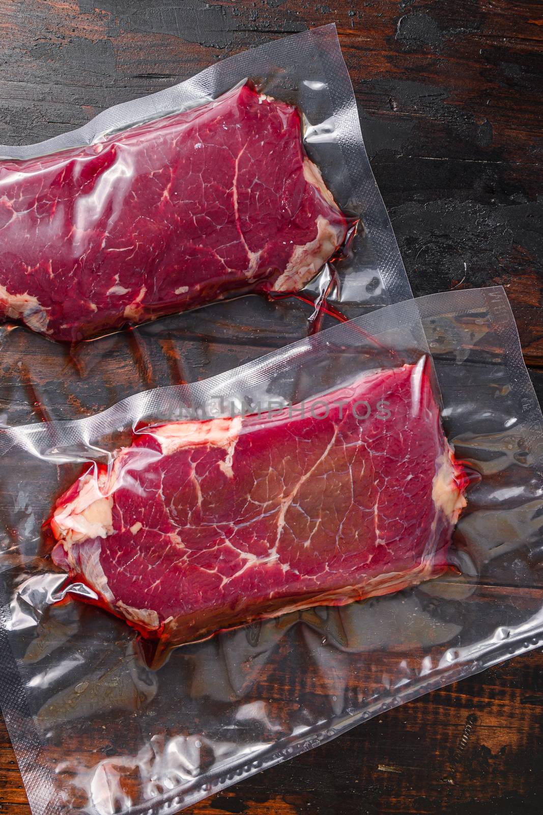 Rump beef steak in vacuum sealed bag on dark old wooden table, top view. by Ilianesolenyi