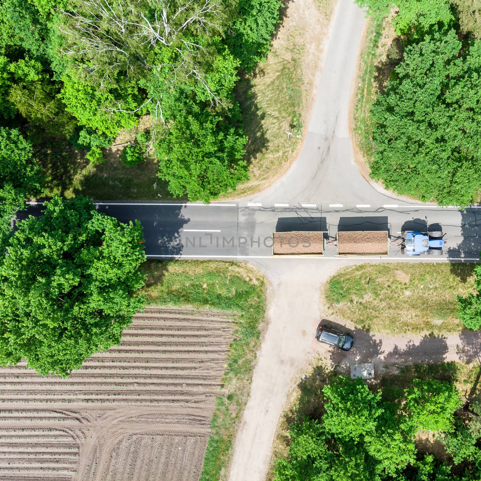 Aerial photo of a crossing in Germany near Celle over which a tractor with two loaded trailers drives, made with drone